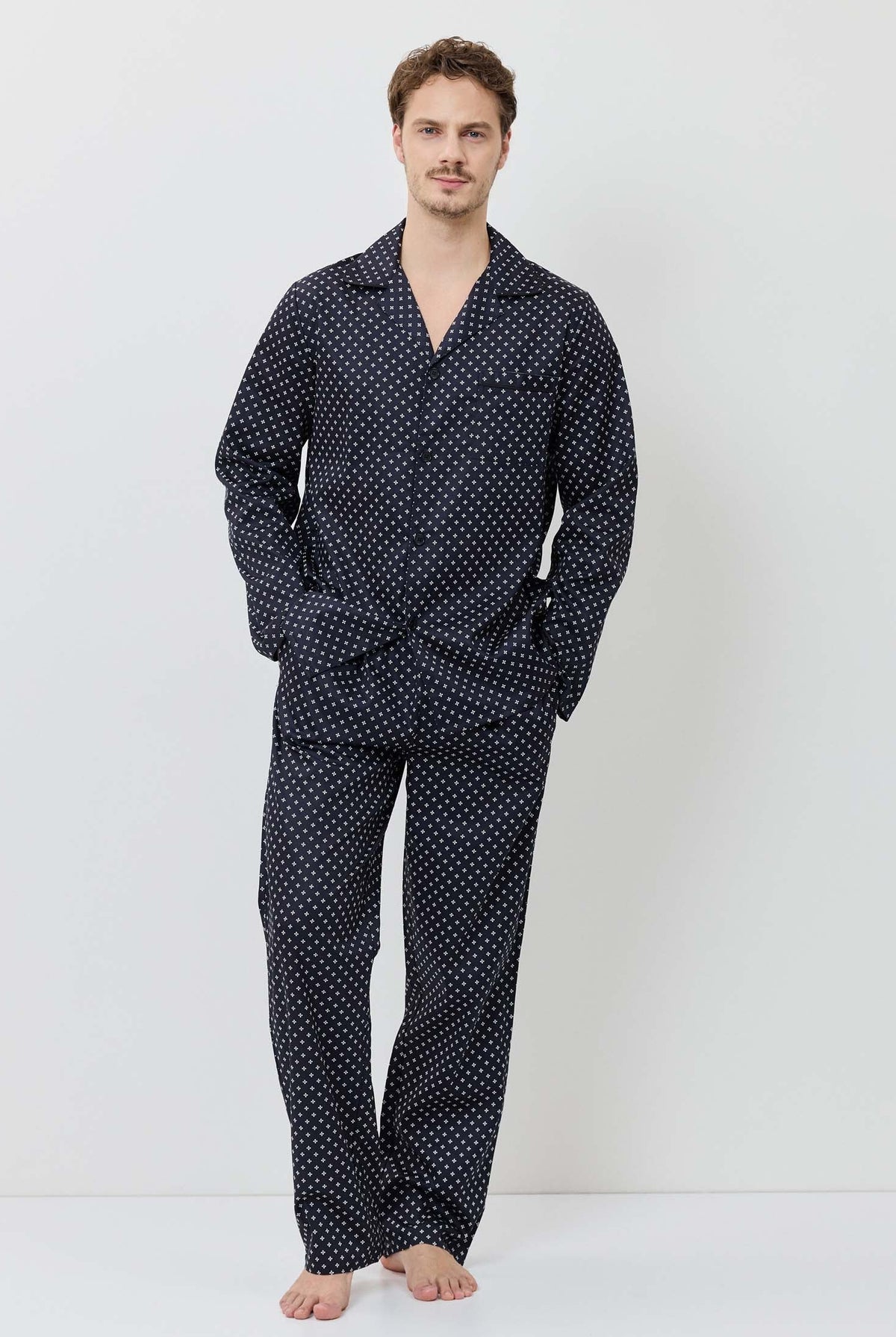 Man wearing a navy polka dot pajama set on a white background