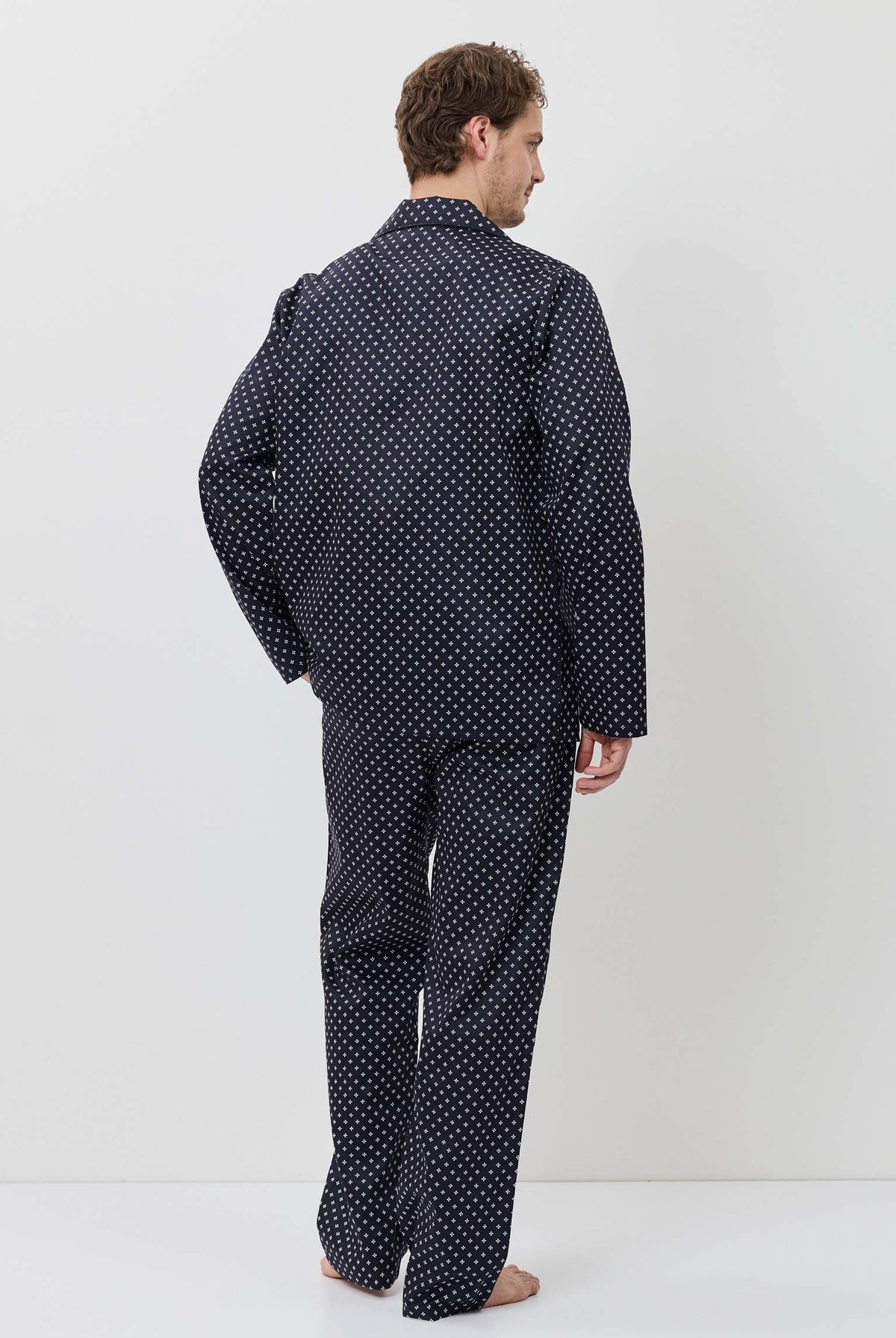 Man wearing a navy polka dot pajama set against a white background