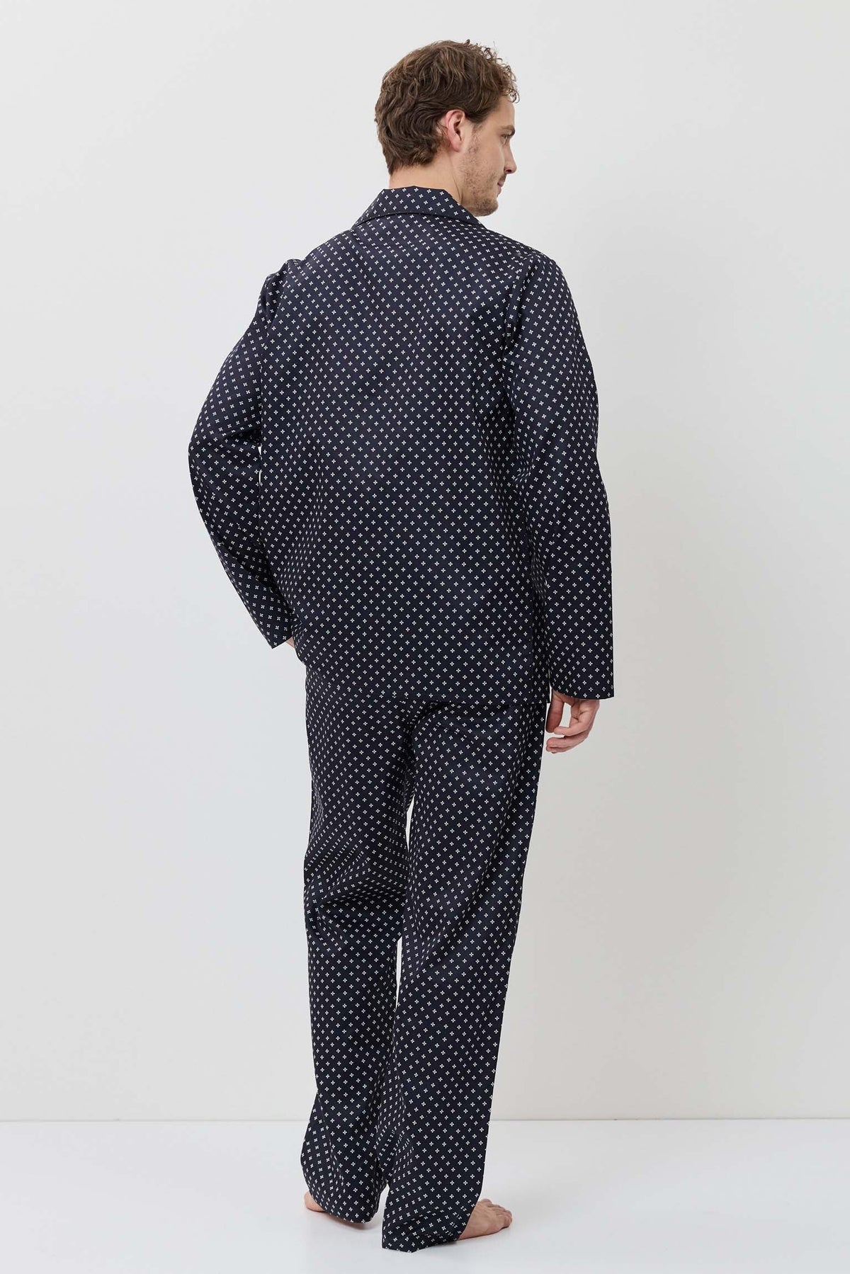 Man wearing a navy polka dot pajama set against a white background