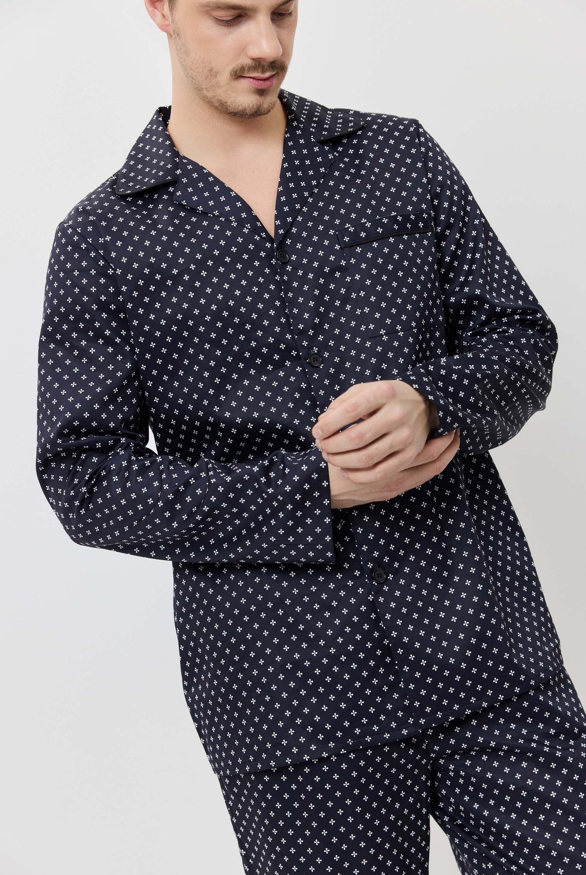 Man wearing a navy blue pajama set with white star pattern on a light gray background
