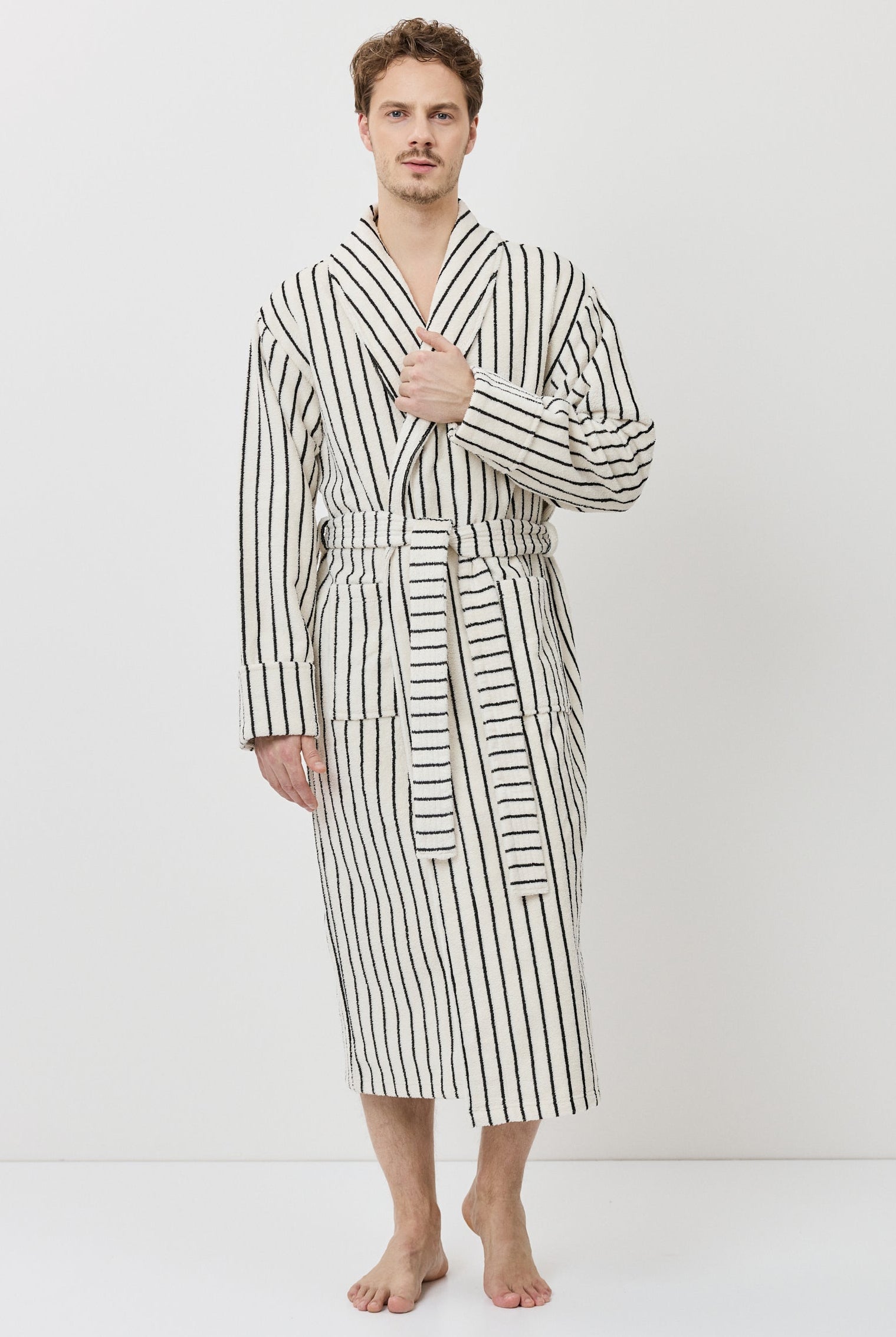 A man wearing a long-sleeved striped bathrobe with black and white vertical stripes.