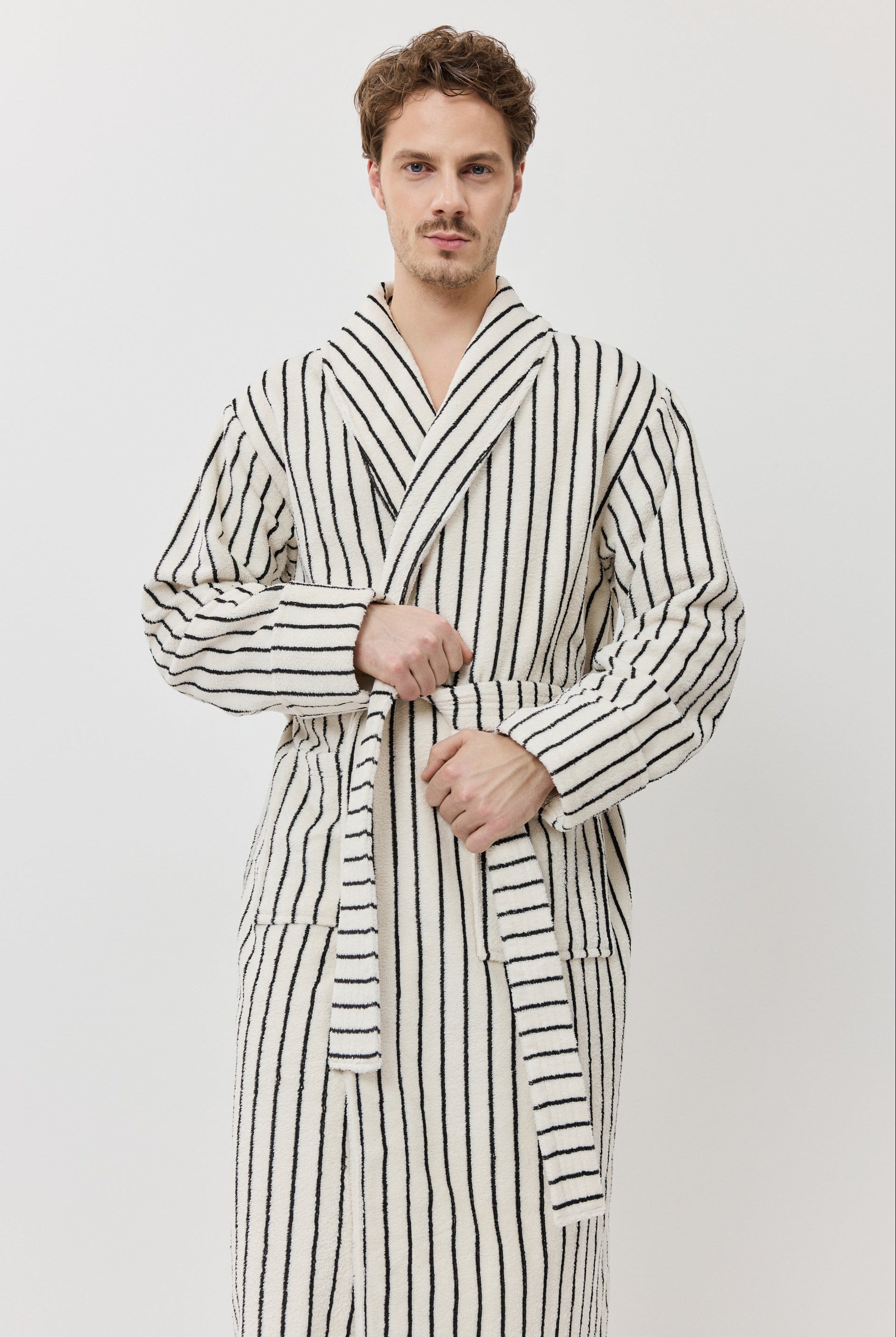 A man wearing a long-sleeved striped bathrobe with black and white vertical stripes.