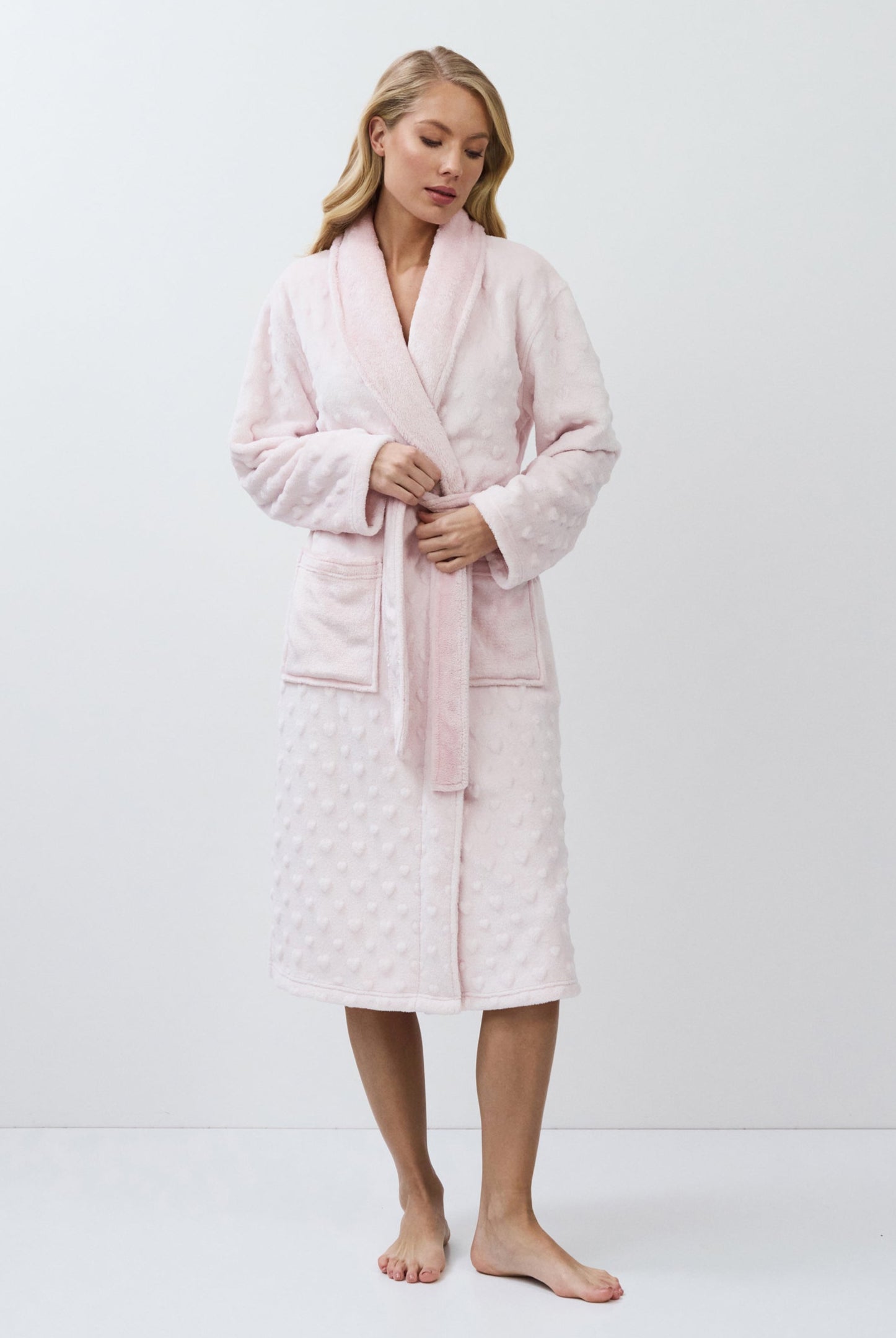 Woman wearing a pink bathrobe against a white background