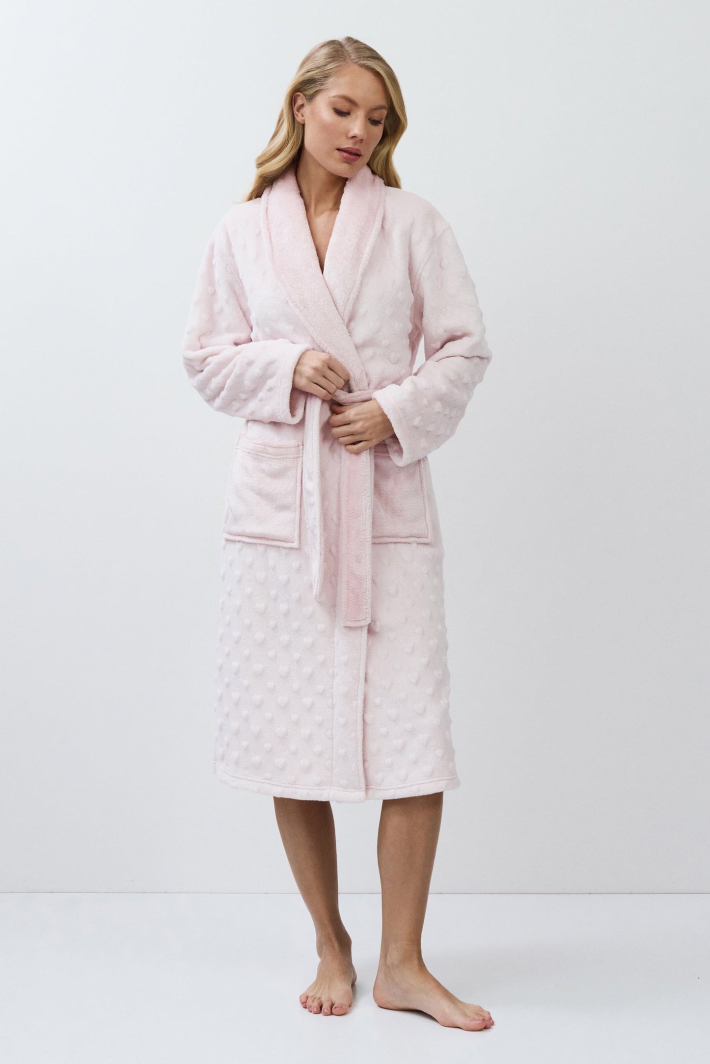 Woman wearing a pink bathrobe against a white background