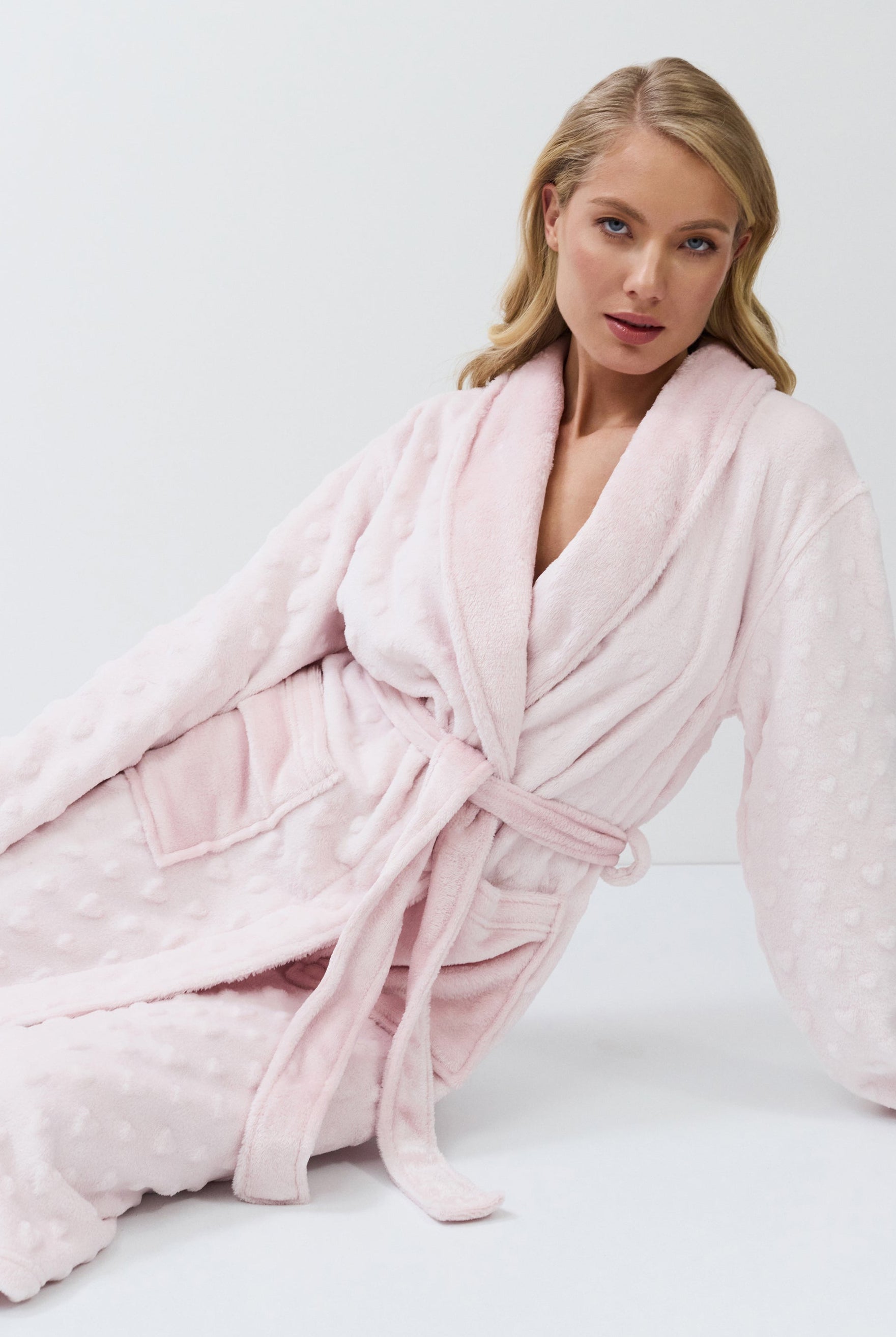 Woman wearing a pink bathrobe against a white background
