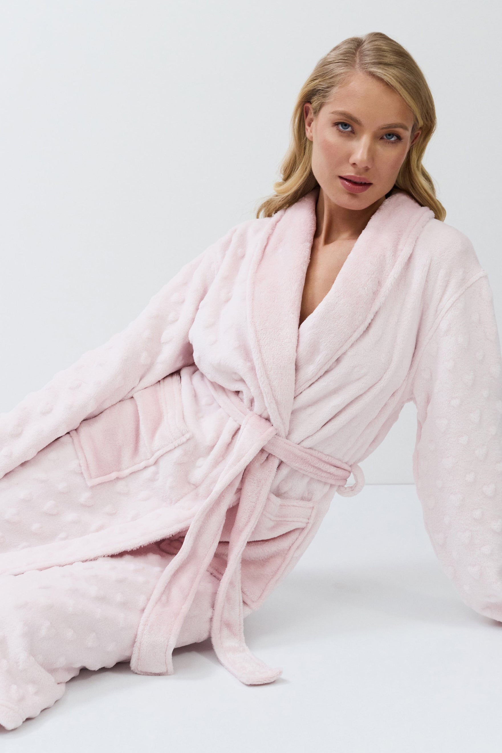 Woman wearing a pink bathrobe against a white background