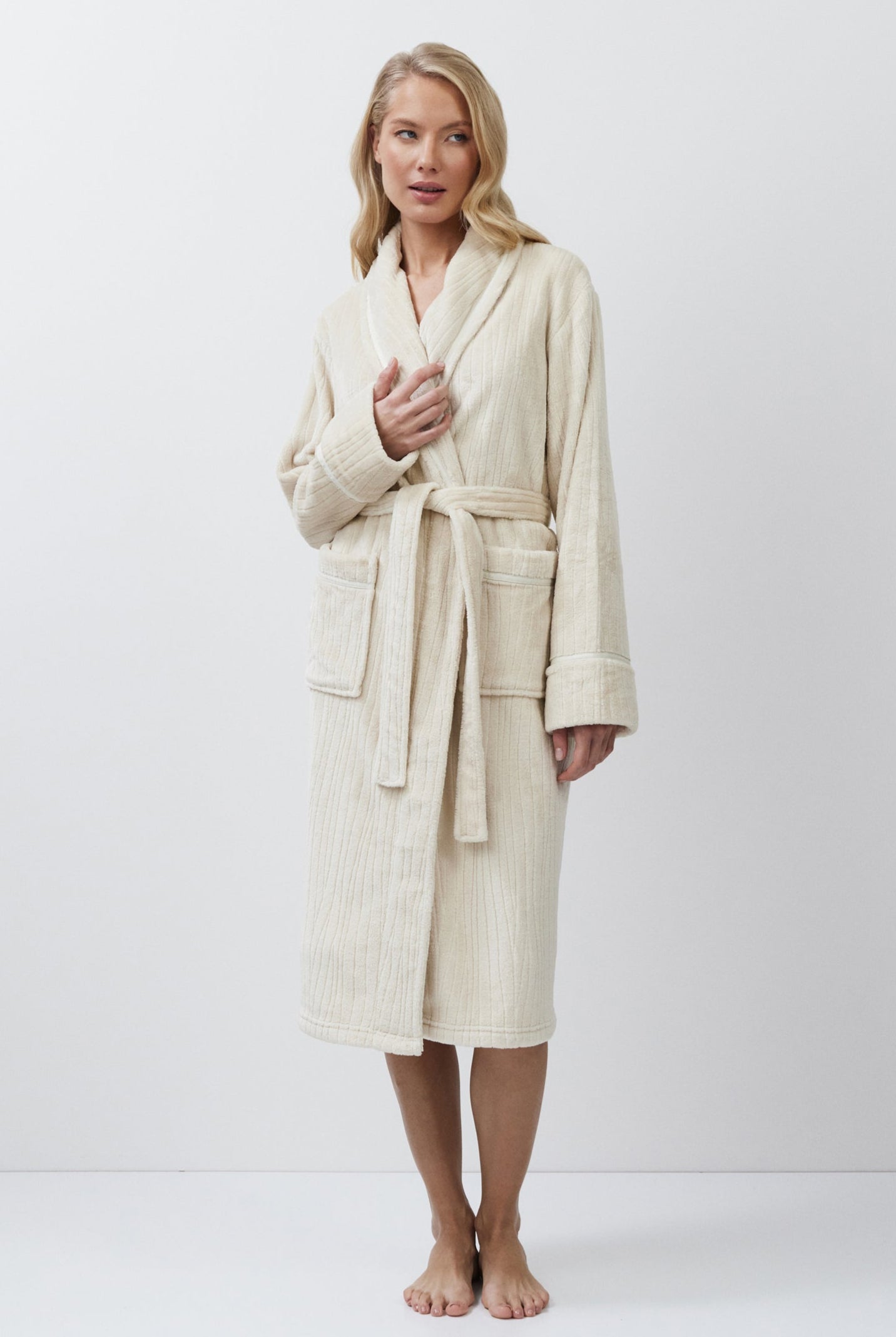 Woman wearing a beige bathrobe against a white background