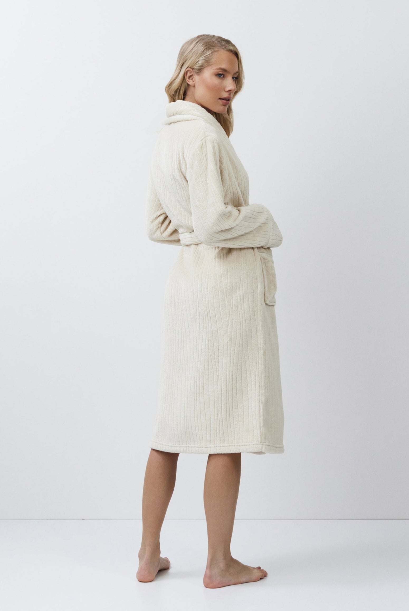 Woman wearing a cream-colored bathrobe against a white background