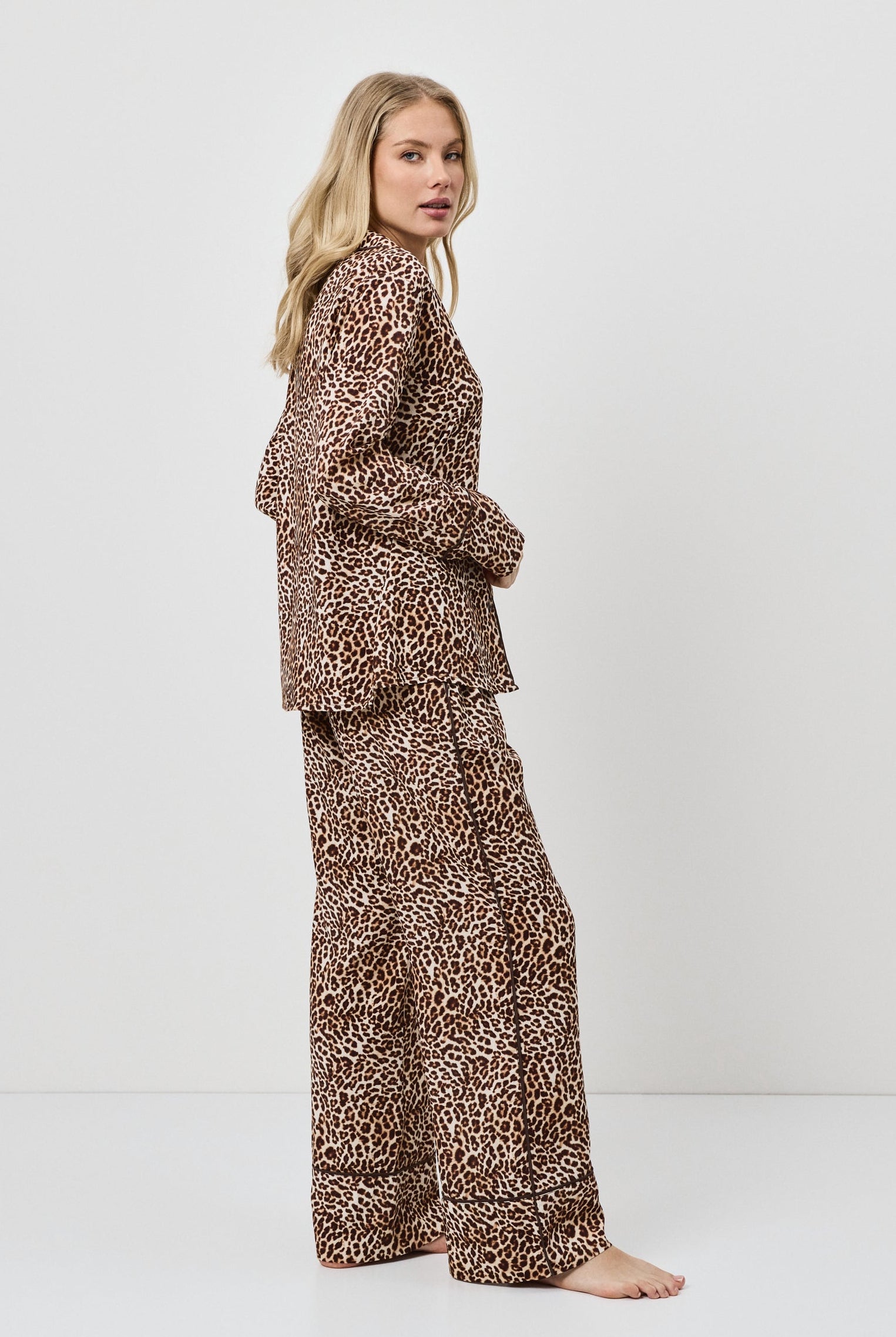Woman wearing a leopard print pajama set on a white background