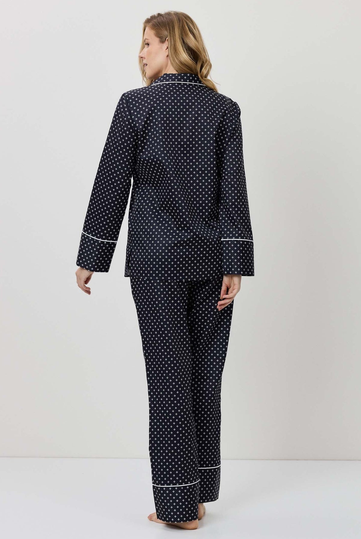 Woman wearing a navy polka dot pajama set against a white background