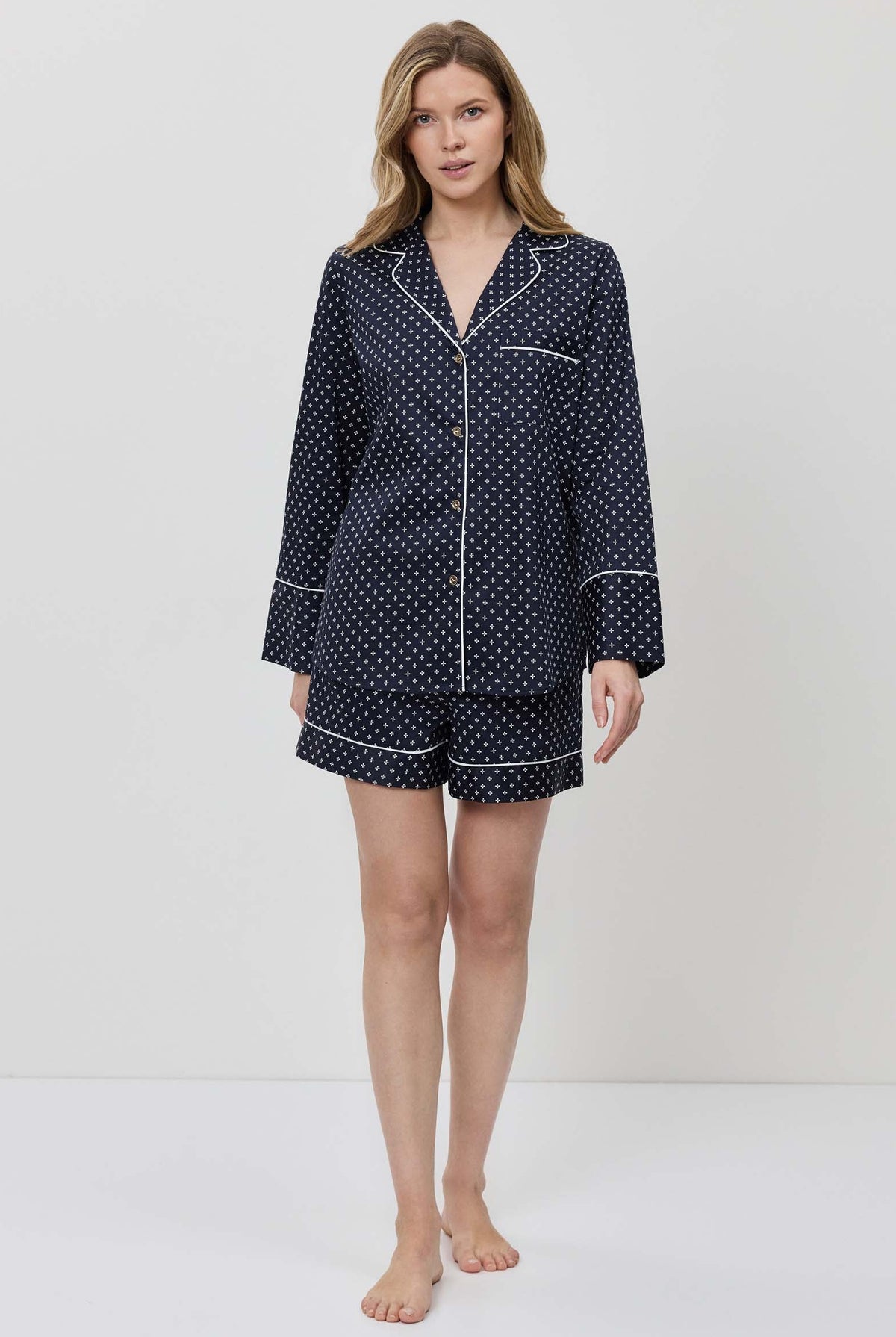 Woman wearing a navy blue polka dot pajama set on a white background