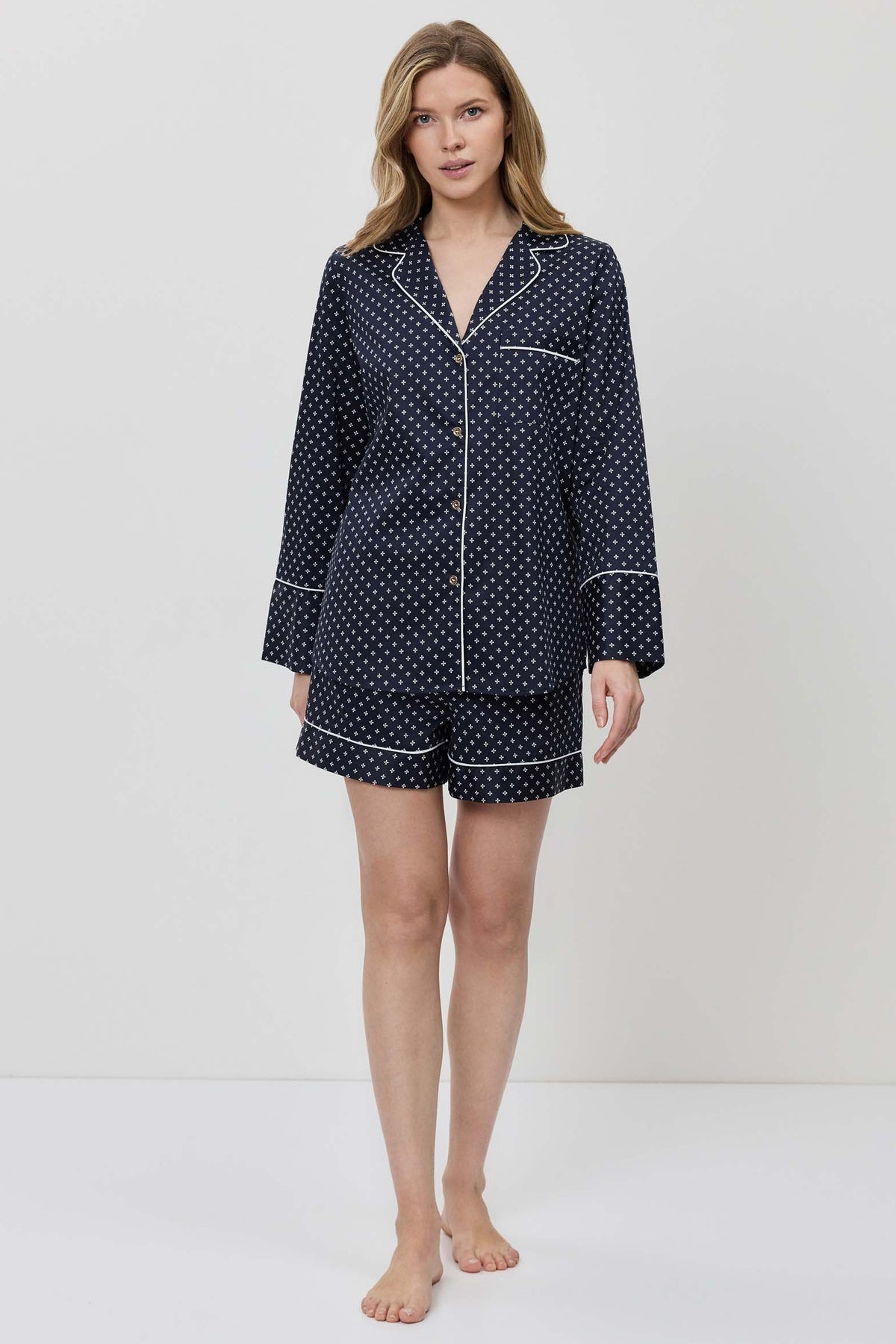 Woman wearing a navy blue polka dot pajama set on a white background
