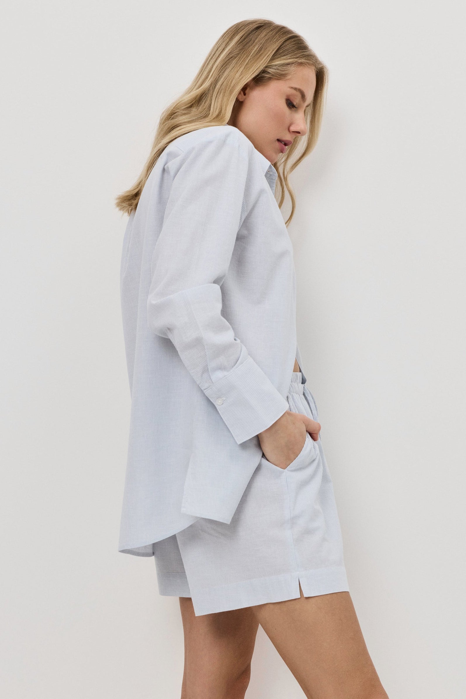 Woman wearing a light blue resort wear set against a white background