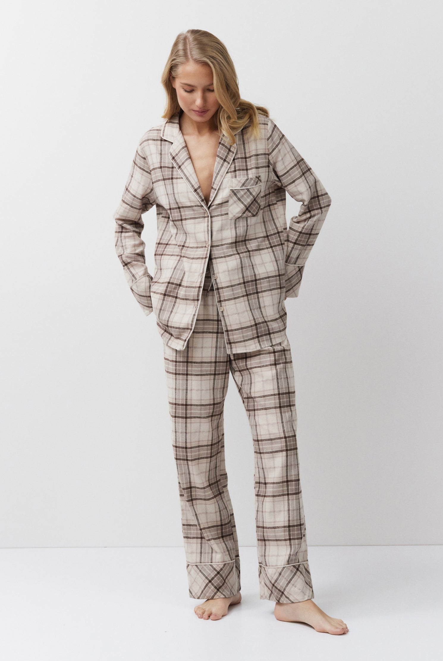 Woman wearing a plaid pajama set standing against a white background