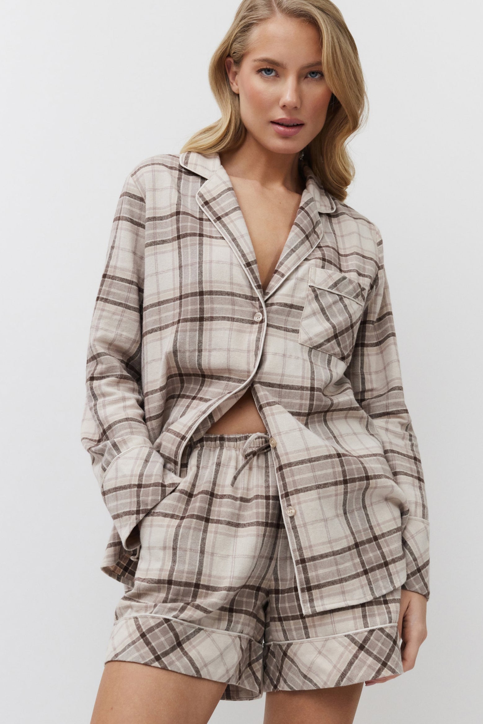 Woman wearing a plaid pajama set against a plain background