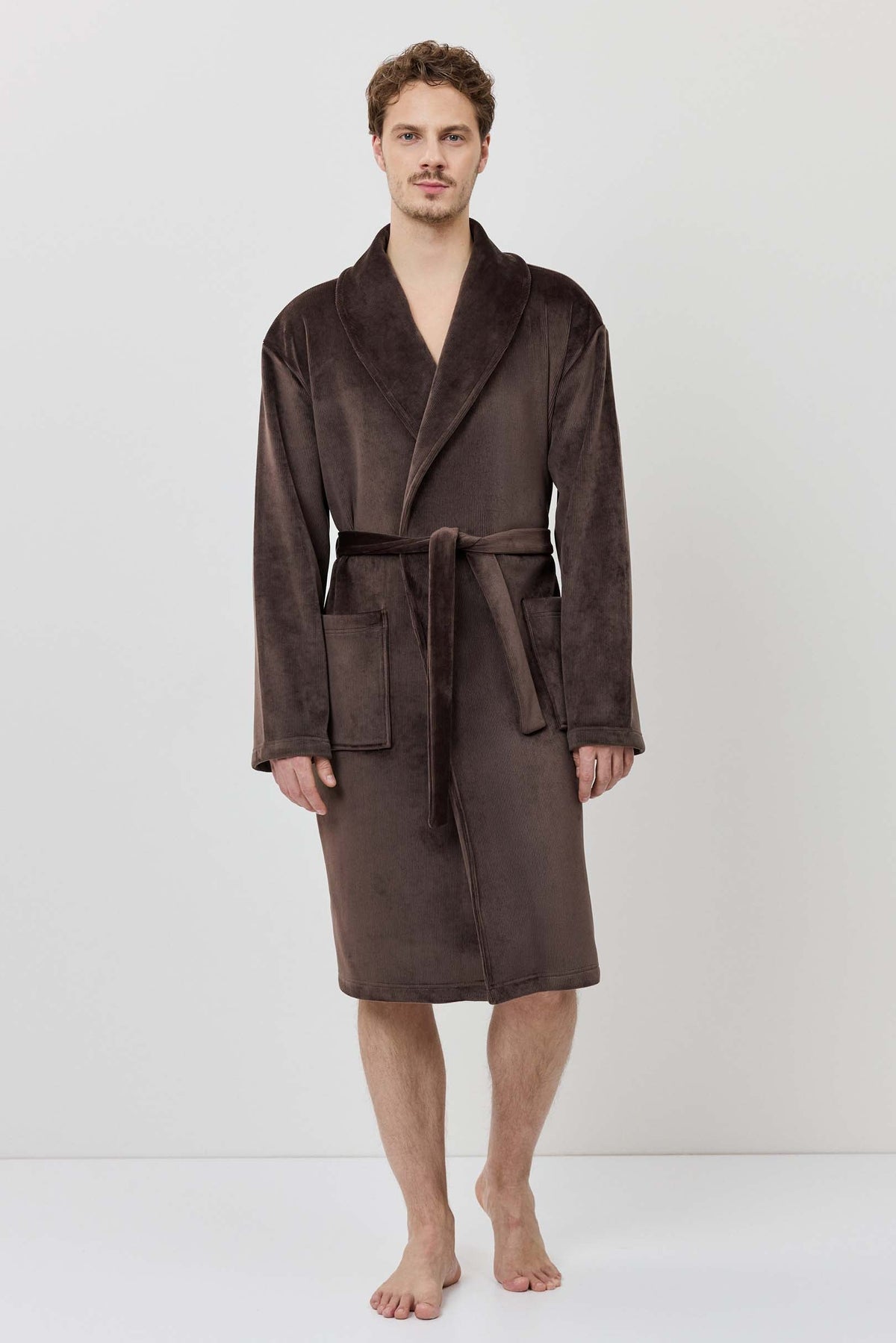 Man wearing a brown robe against a white background