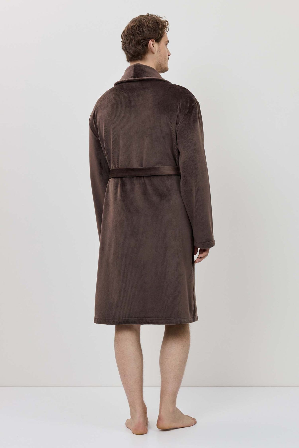 Person wearing a brown robe standing against a white background