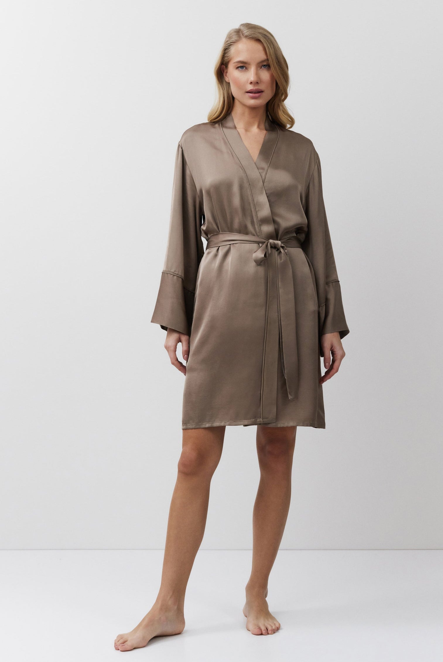 Woman wearing a brown satin gown against a white background