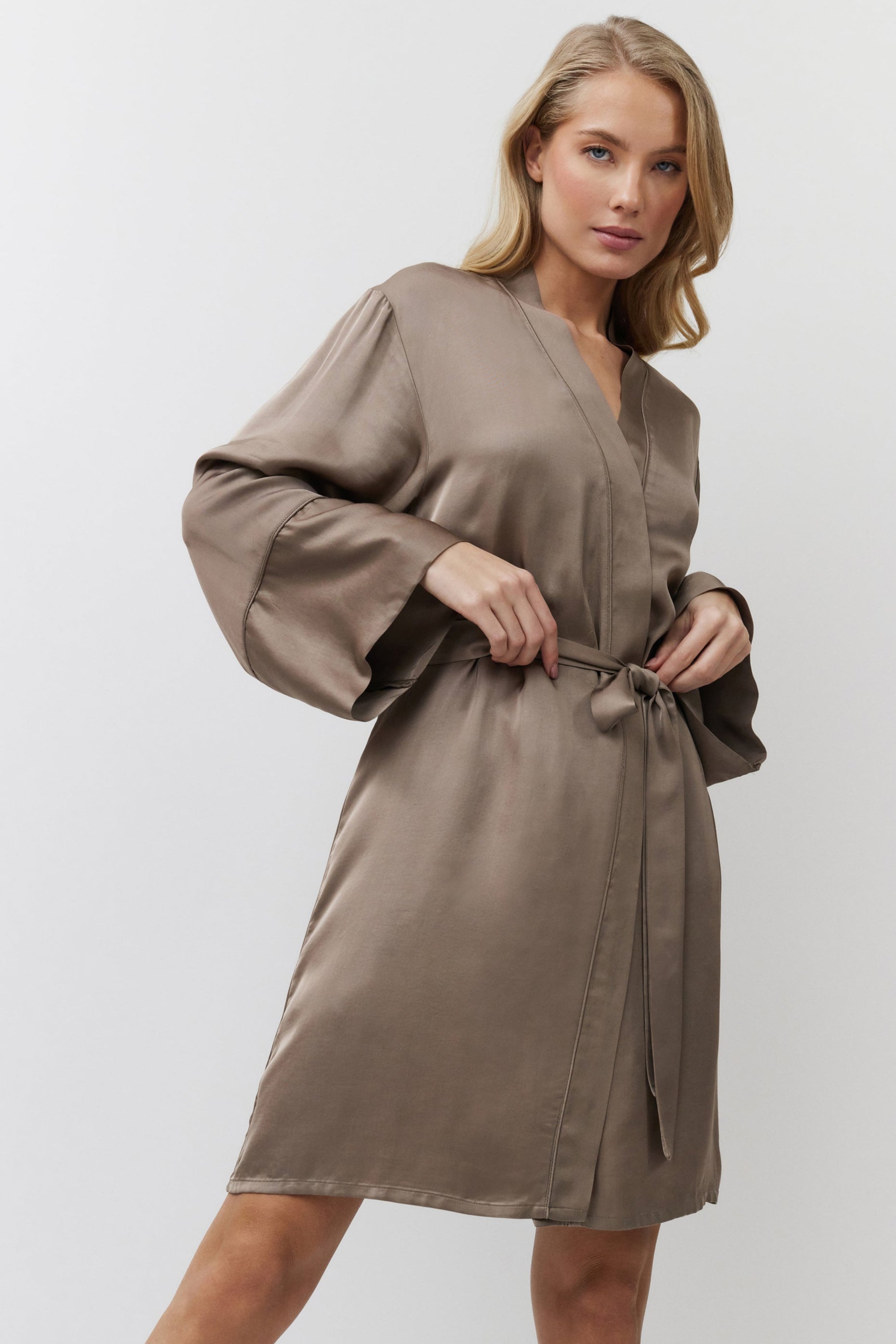 Woman wearing a brown satin gown against a white background