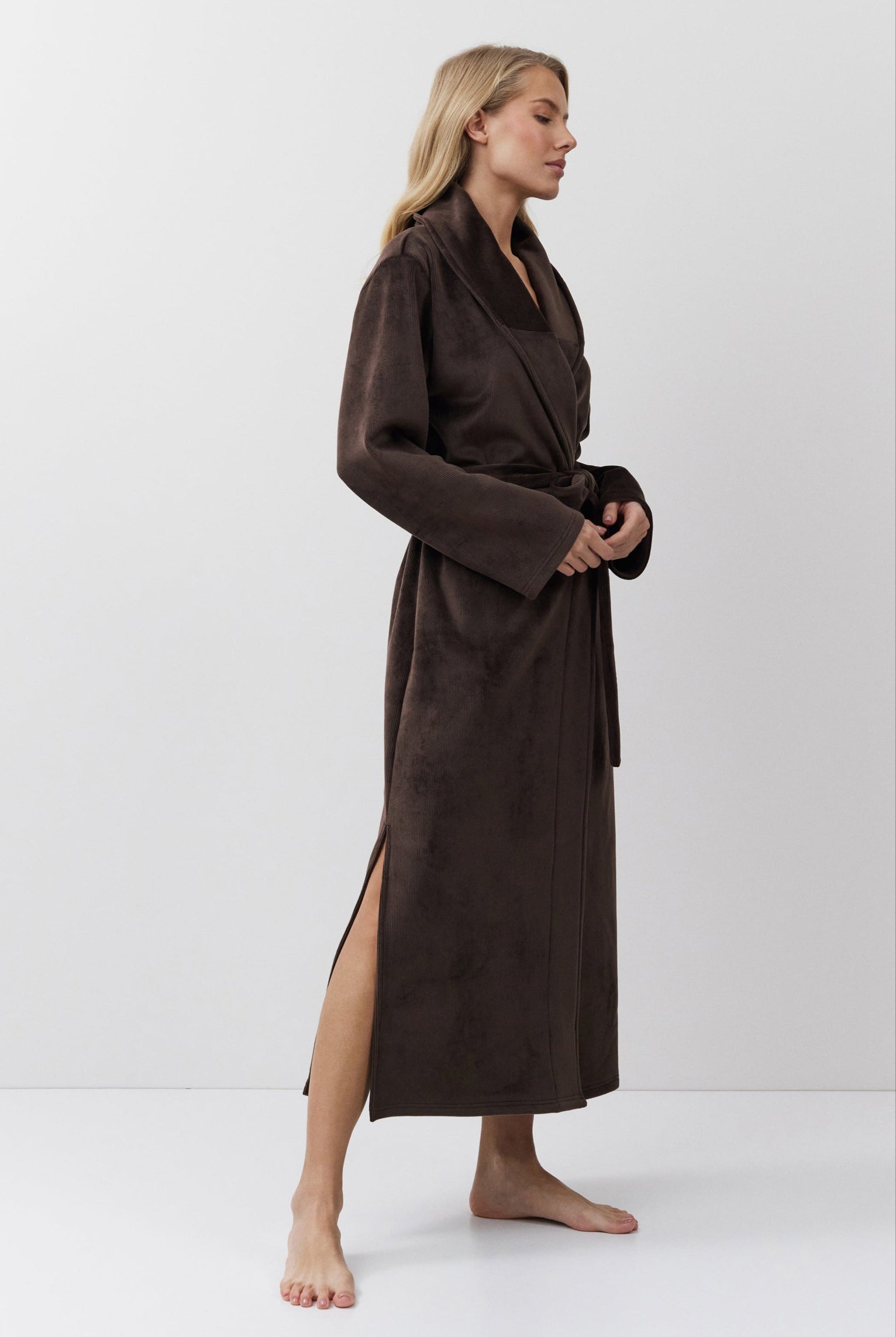 Woman wearing a brown bathrobe against a white background