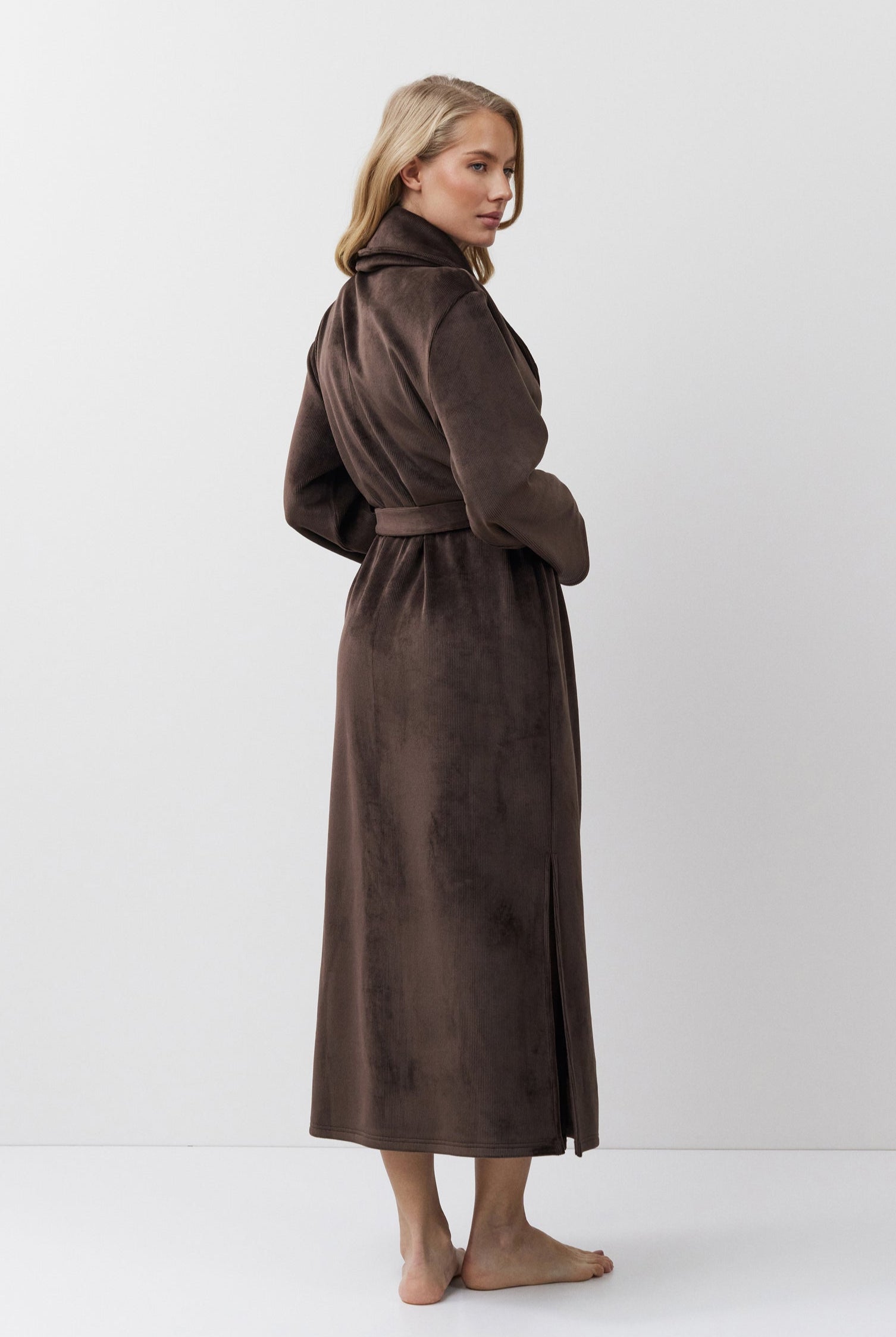 Woman wearing a brown bathrobe against a white background