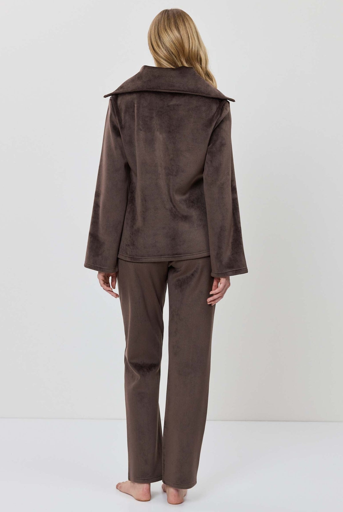 A woman modeling a matching two-piece lounge set in dark brown, featuring a long-sleeve half-zip pullover and coordinating pants.
