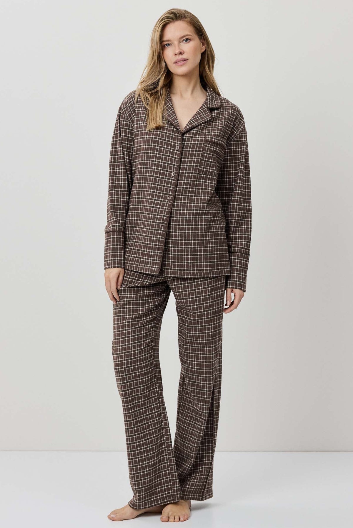 Woman wearing a brown checkered pajama set on a white background