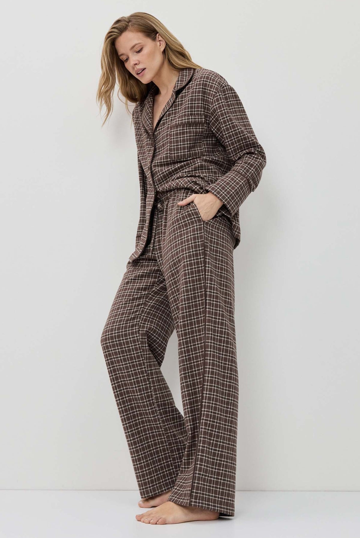 Woman wearing a brown checkered pajama set against a white background