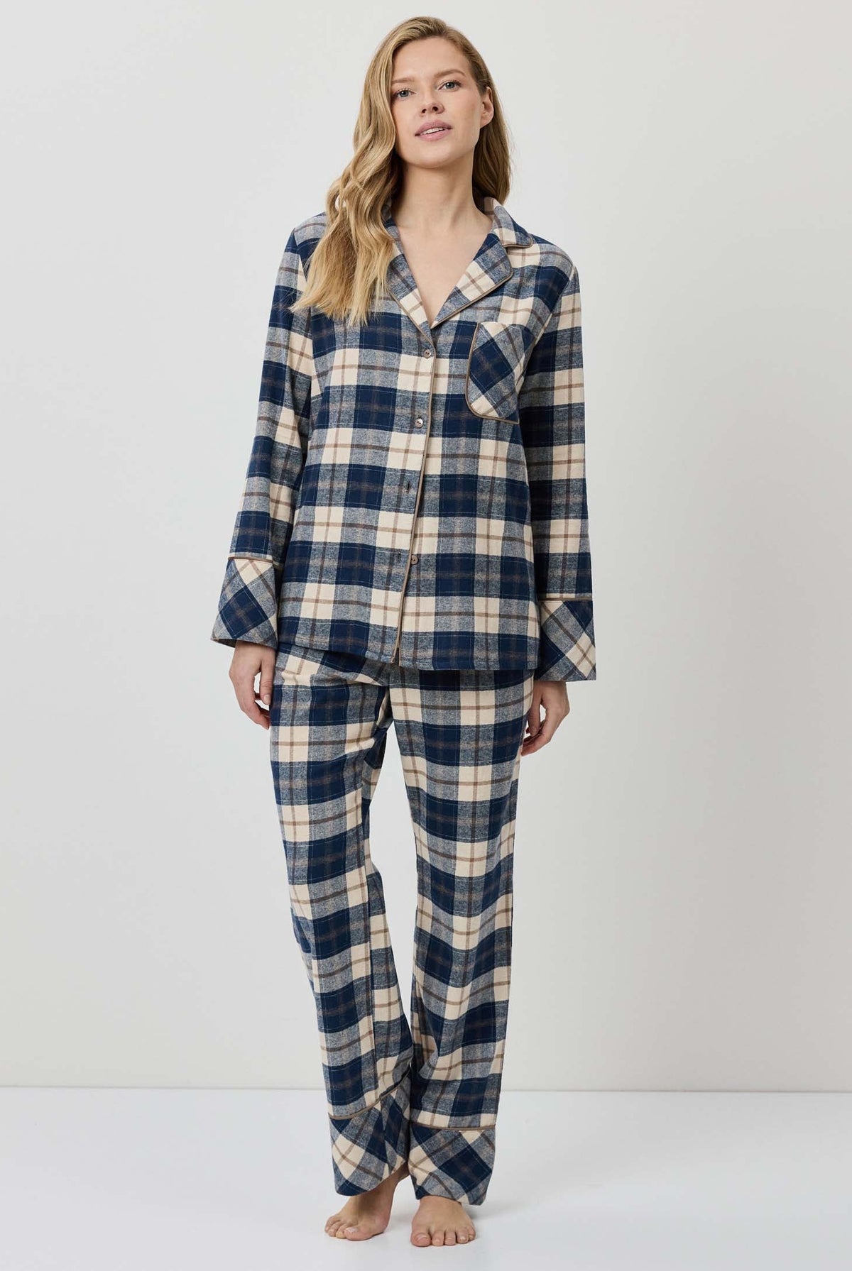 Woman wearing a blue and beige plaid pajama set on a white background