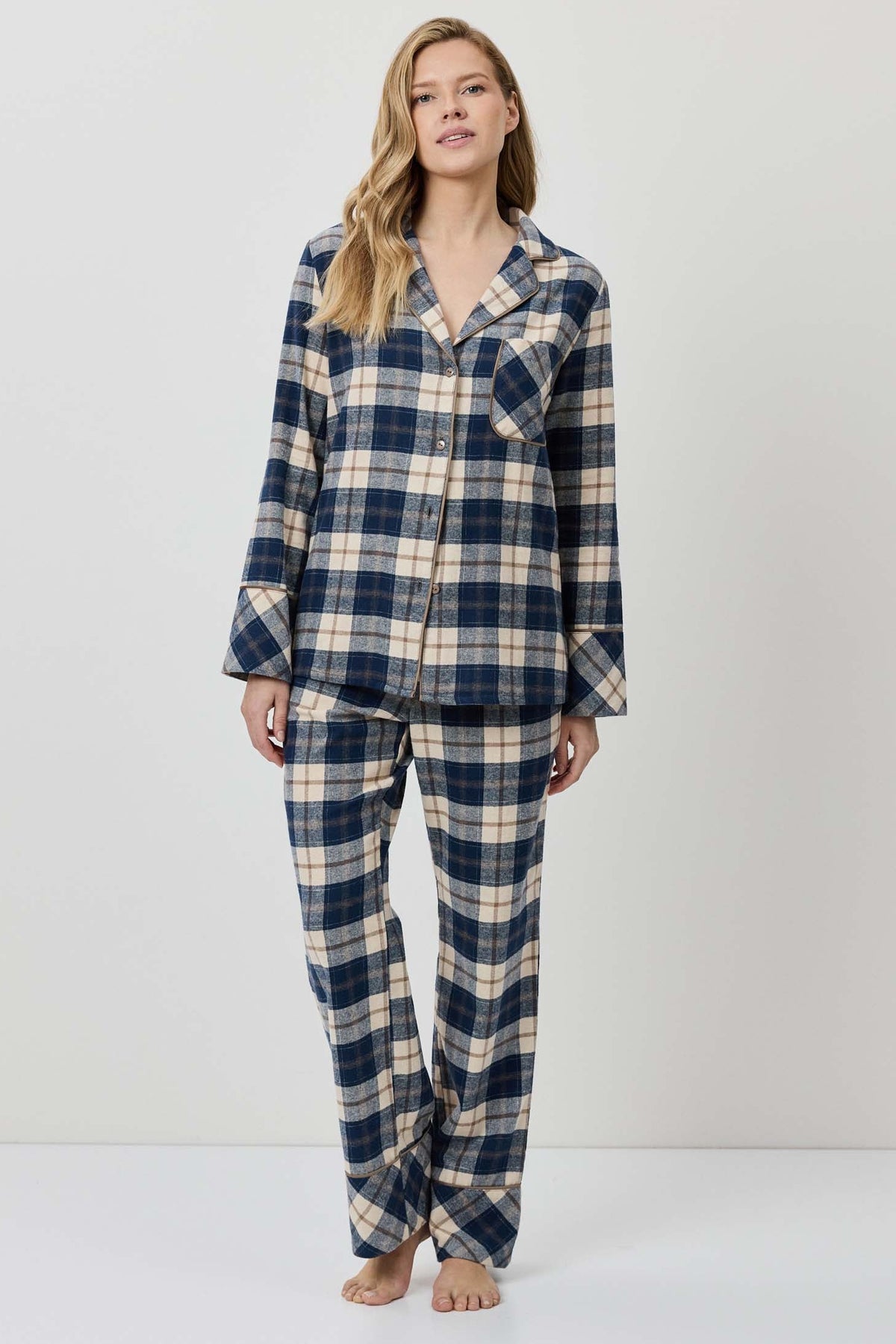 Woman wearing a blue and beige plaid pajama set on a white background