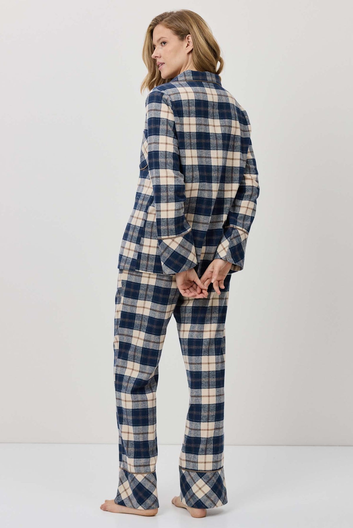 Woman wearing a blue and white plaid pajama set against a plain background