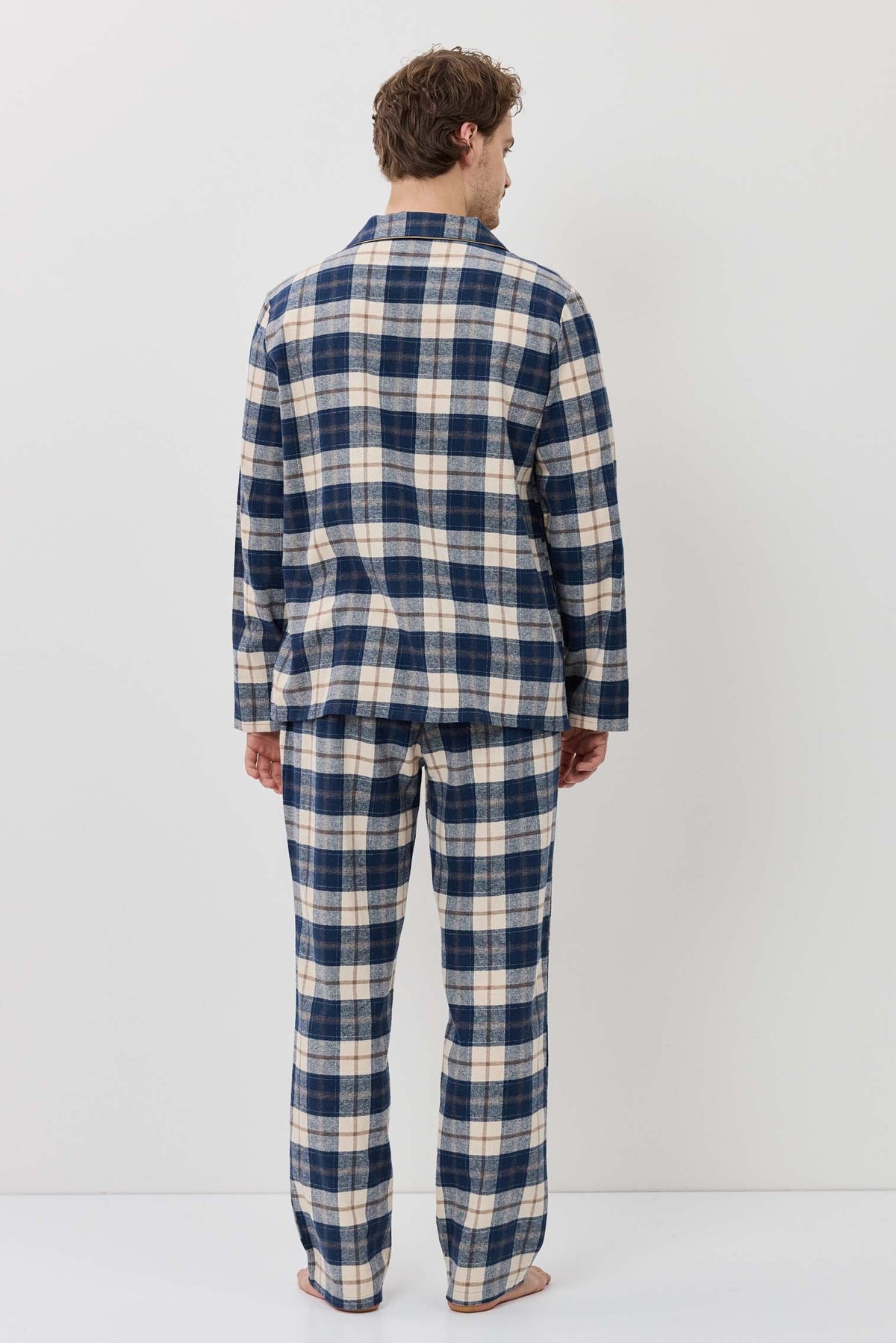 Person wearing a blue and white plaid pajama set against a white background