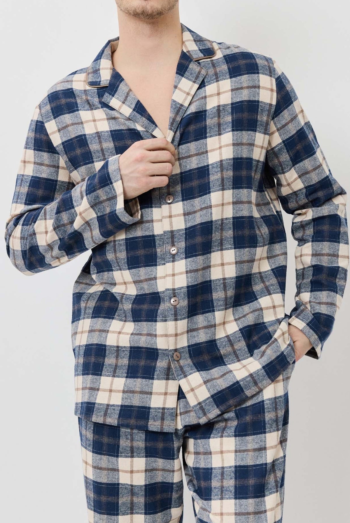 Man wearing a blue and white plaid pajama set against a plain background