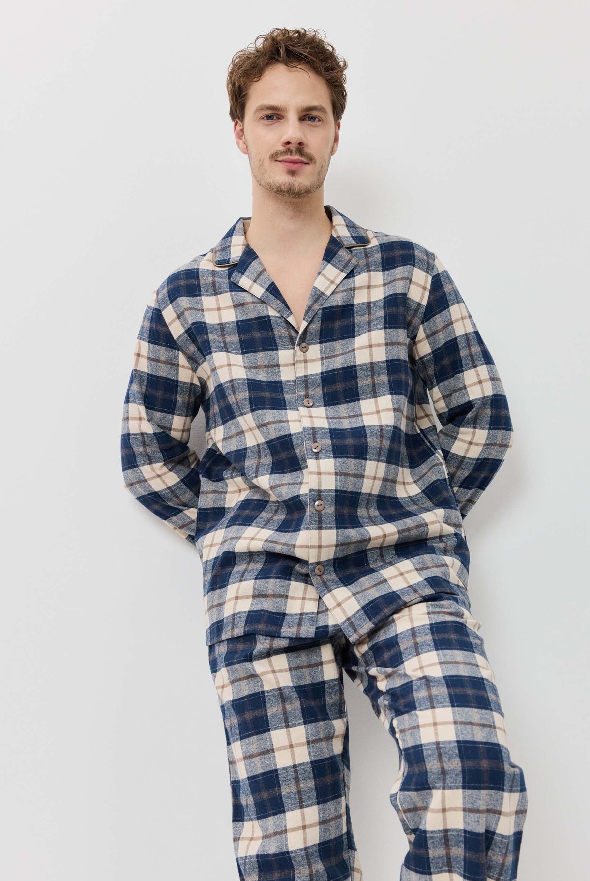 Man wearing a blue and white plaid pajama set against a plain background