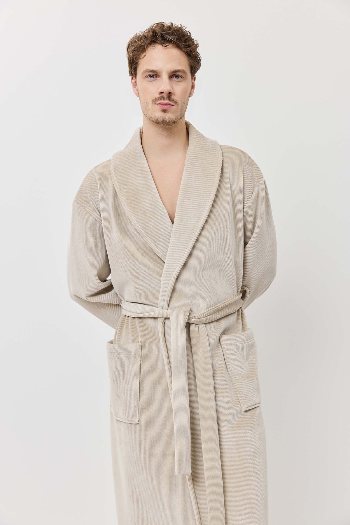 Man wearing a beige robe against a white background