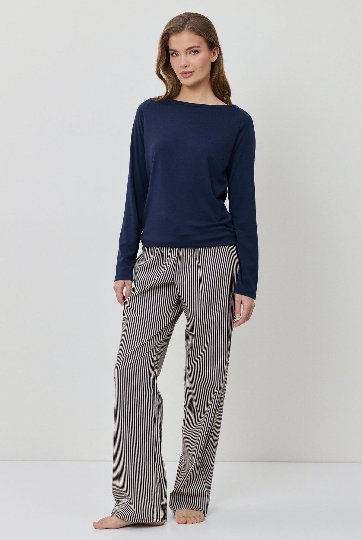 Woman wearing a navy sweater and gray checkered pants on a white background