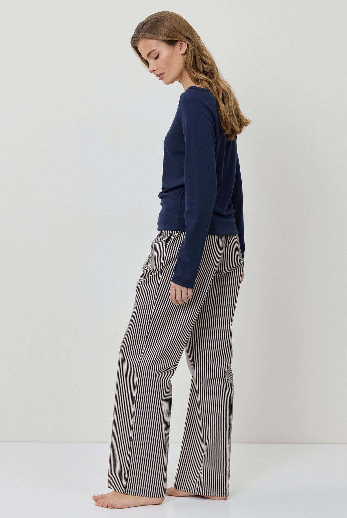 Woman wearing a navy sweater and gray checkered pants on a white background