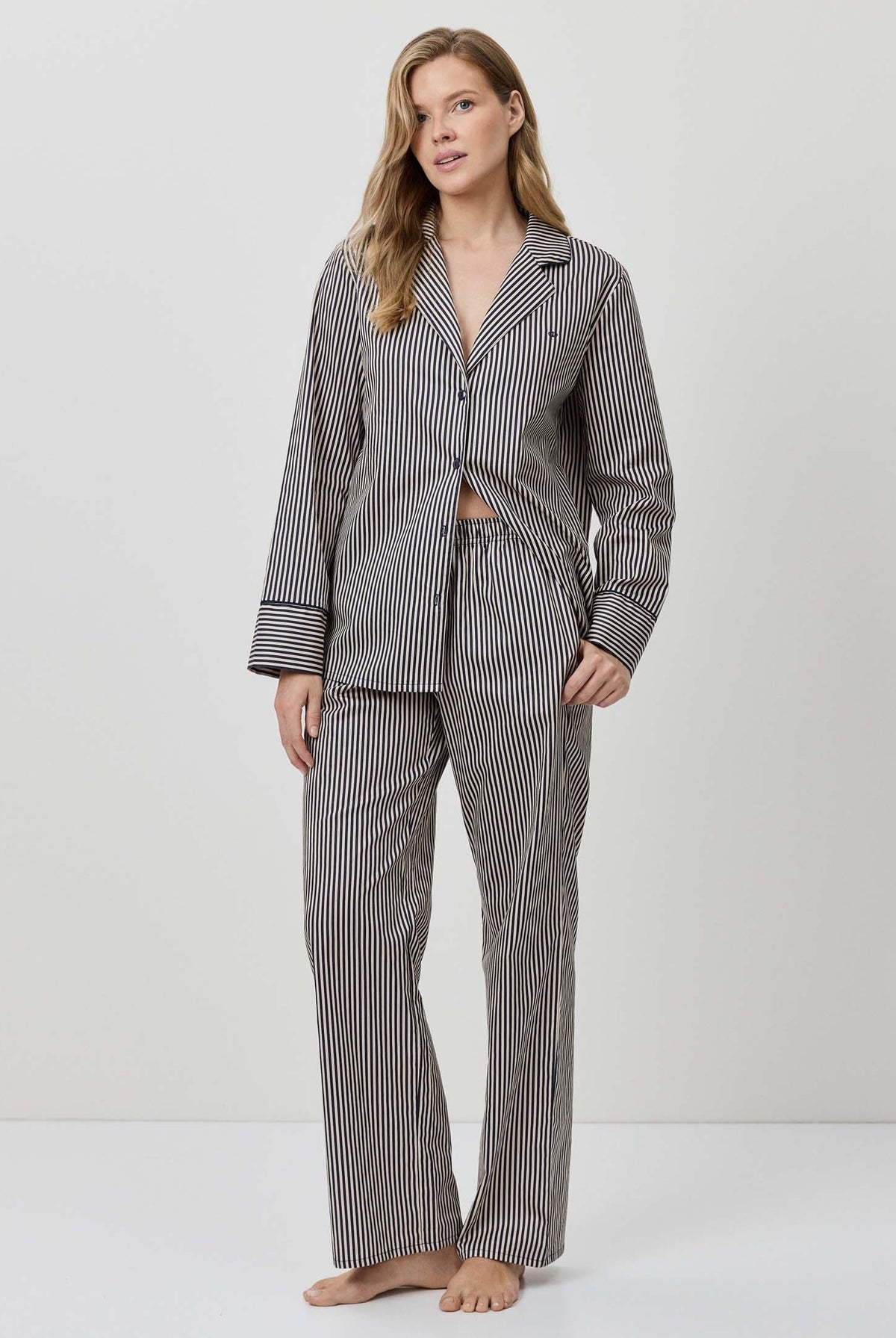 Woman wearing a gray striped pajama set on a white background