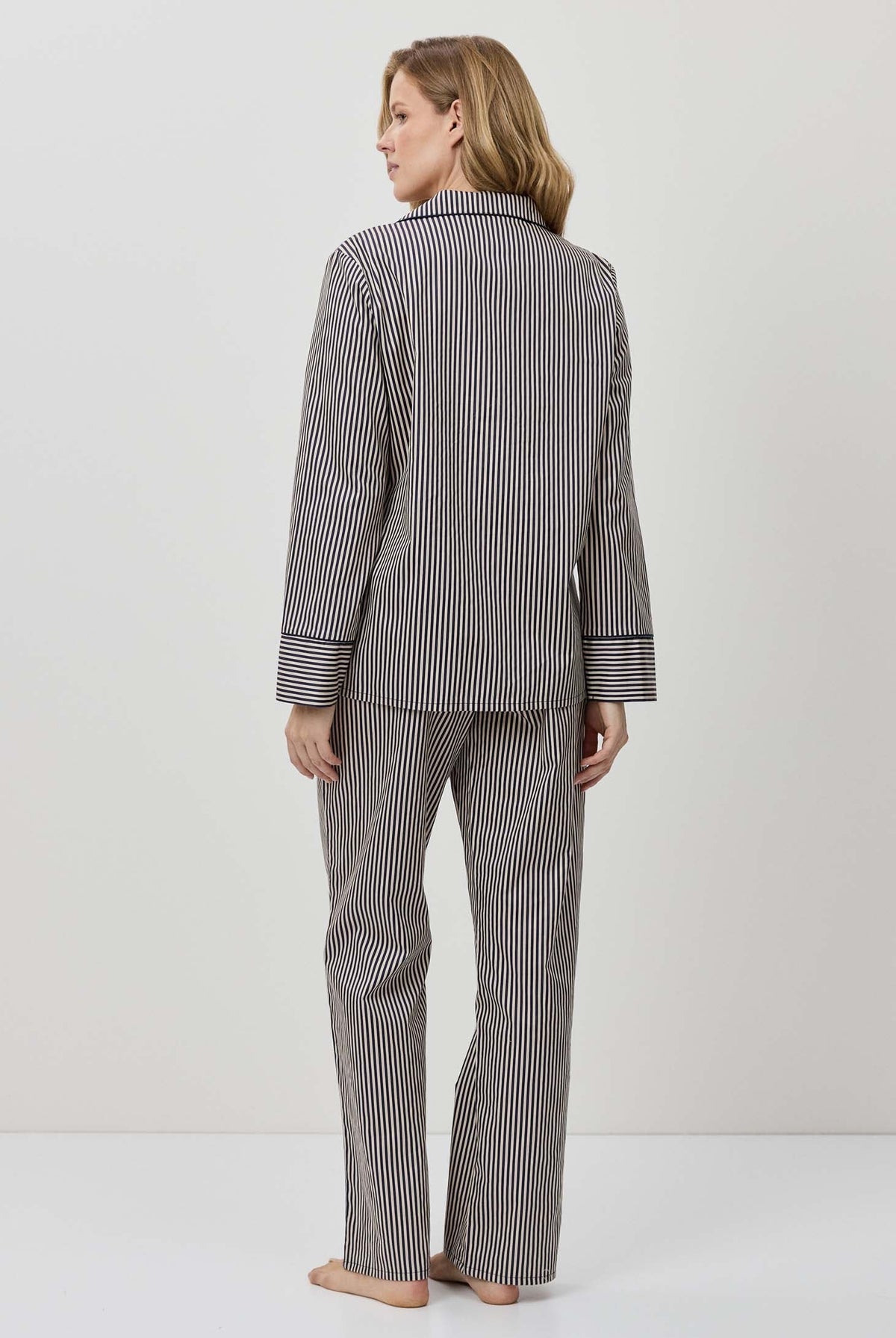 Woman wearing a gray striped pajama set against a white background