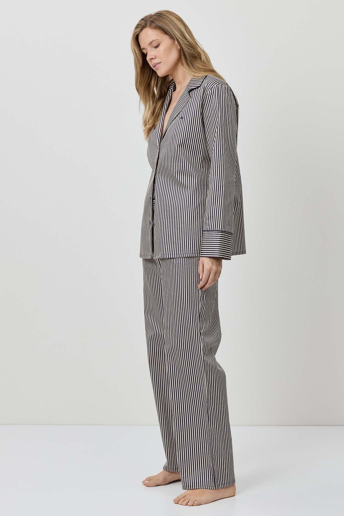 Woman wearing a gray striped pajama set on a white background