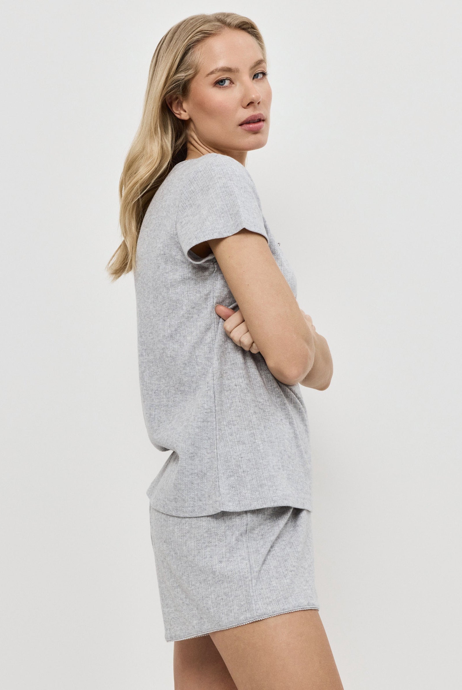 Woman wearing a gray pajama set on a white background