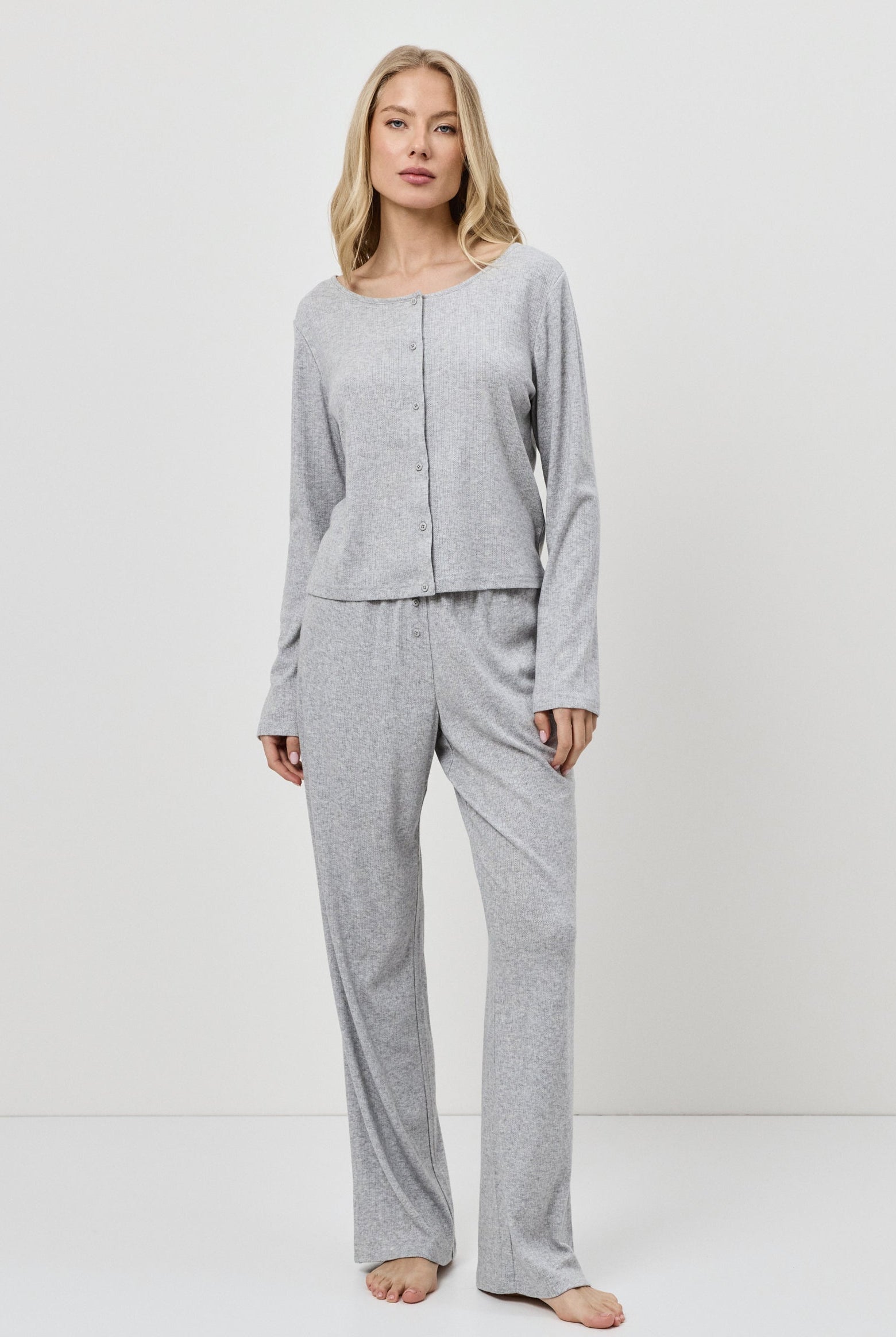 Woman wearing a gray pajama set against a white background