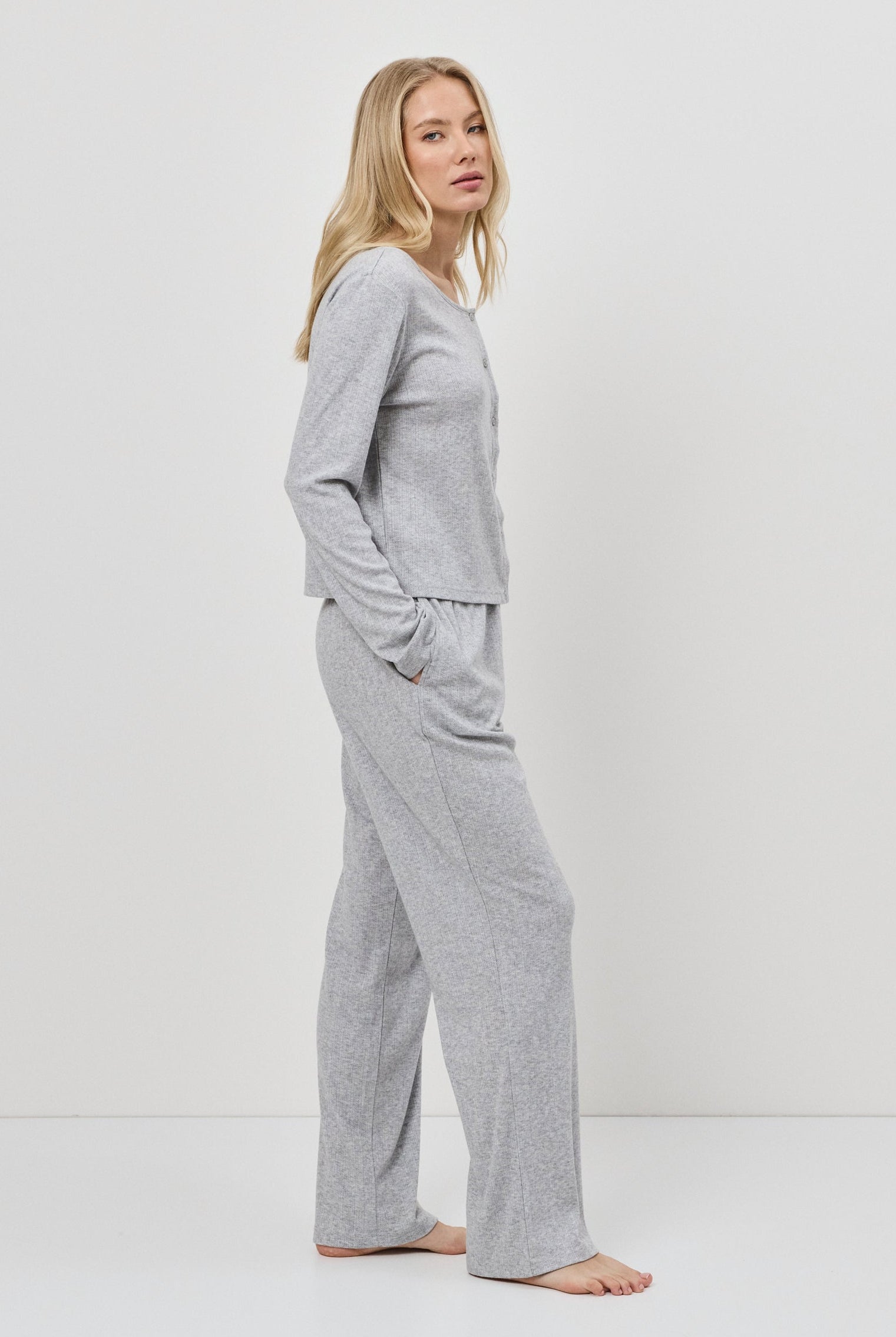 Woman wearing a gray pajama set against a white background