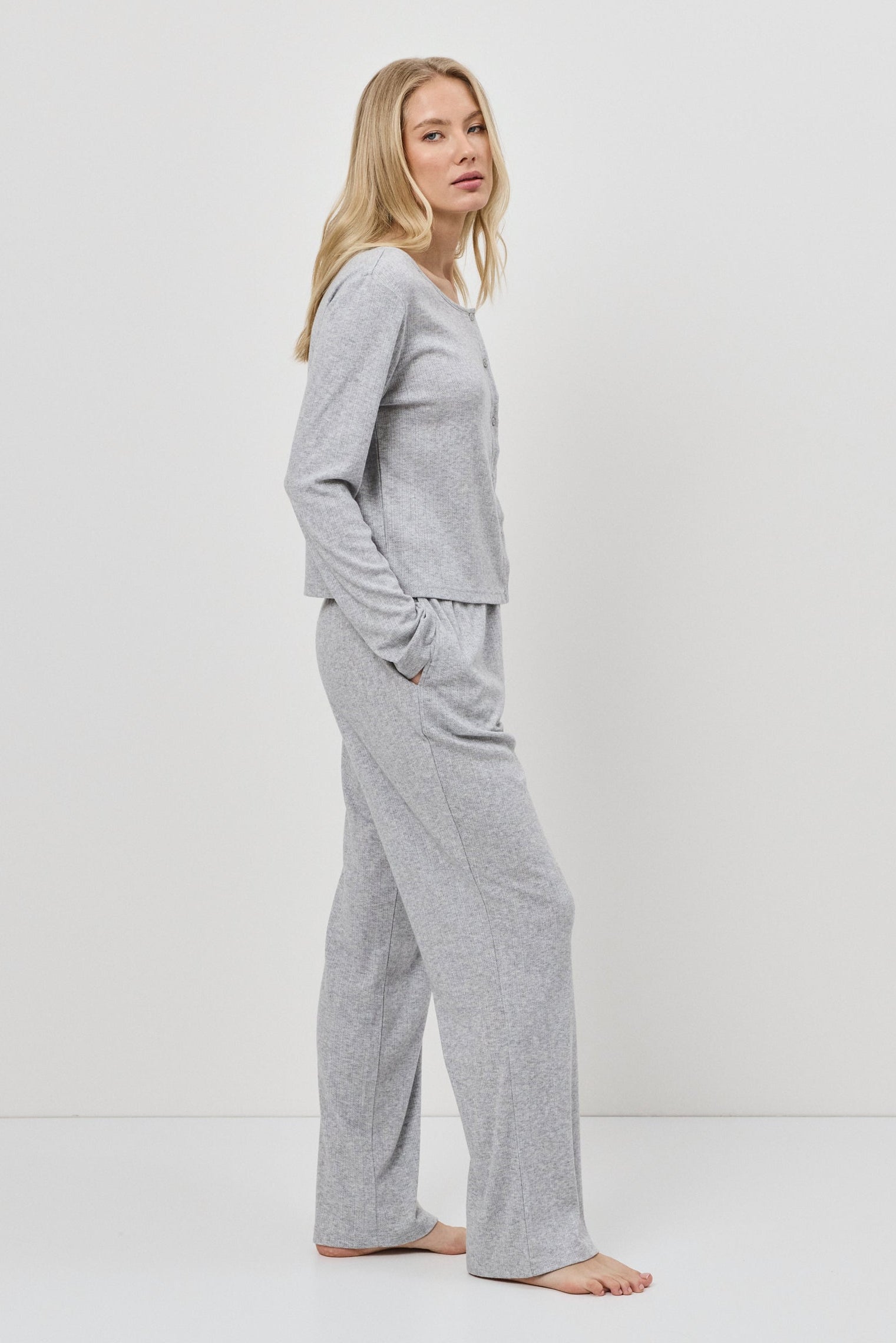 Woman wearing a gray pajama set against a white background