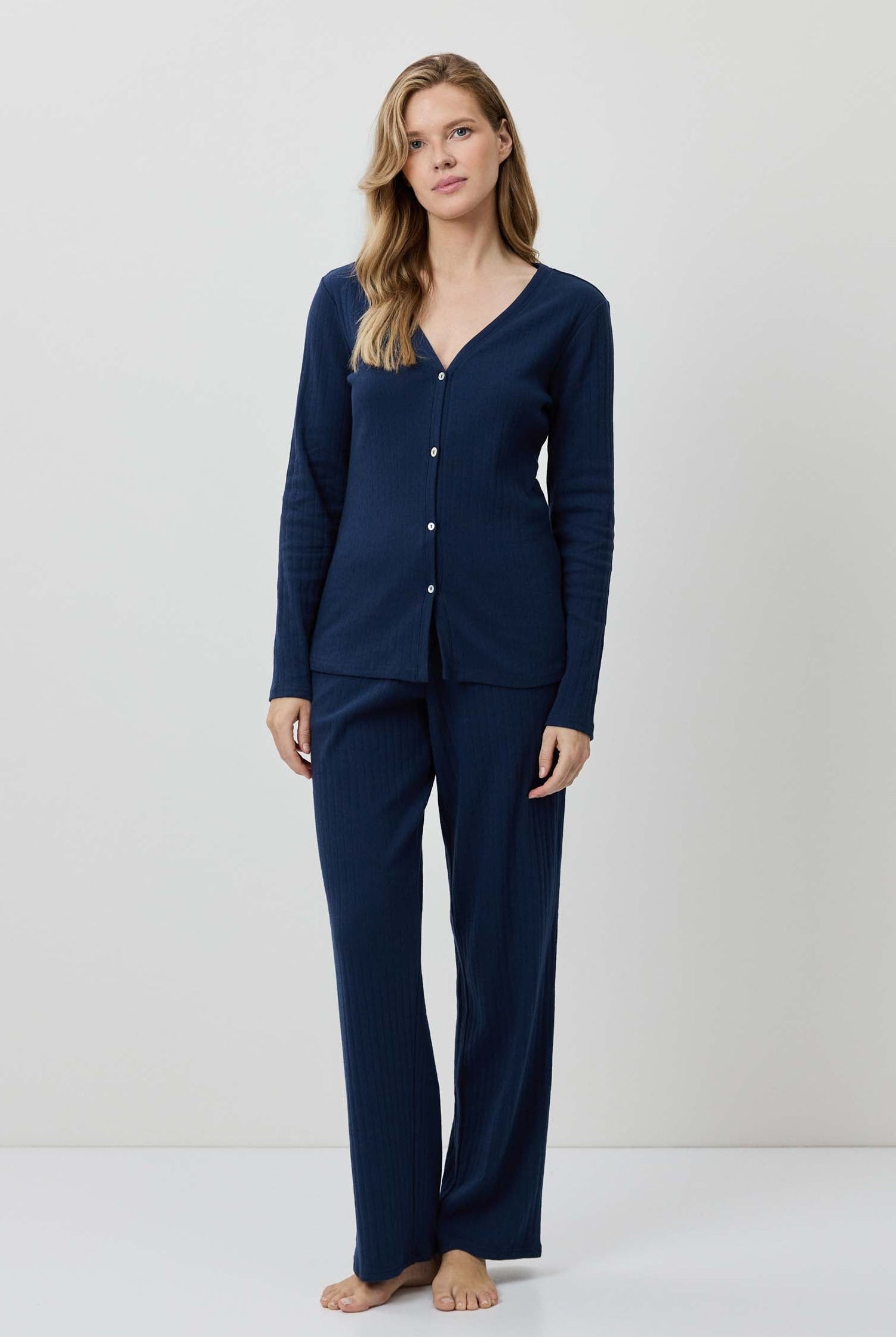 Woman wearing a navy blue pajama set against a white background