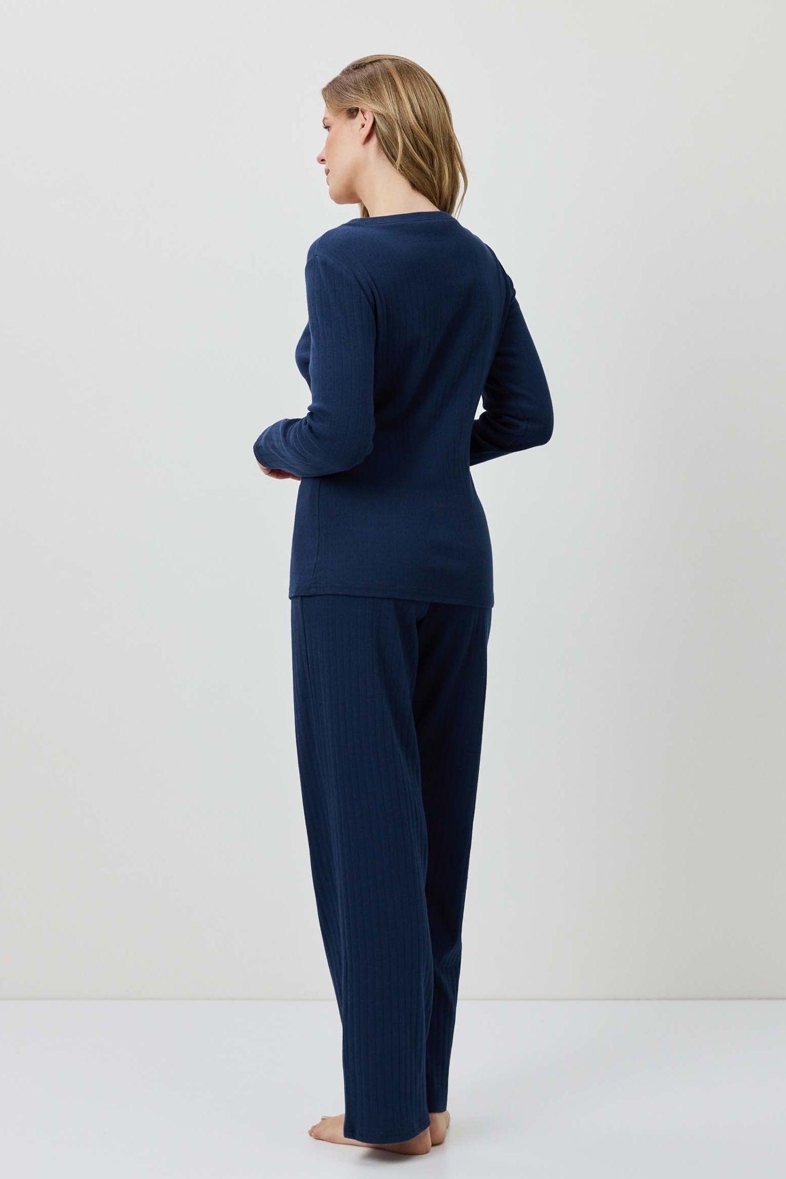 Person wearing a navy blue outfit standing against a white background