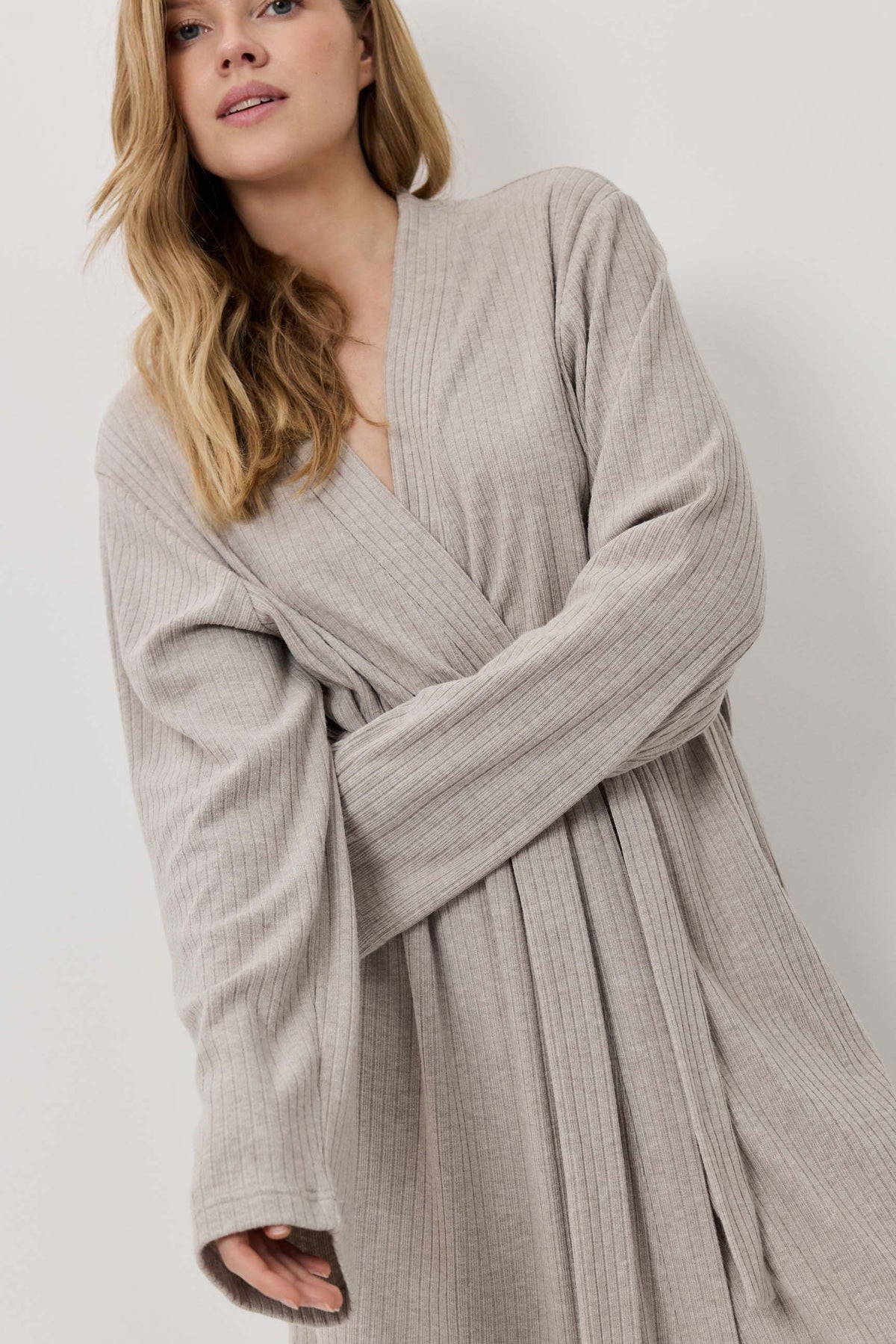 Woman wearing a beige robe against a white background