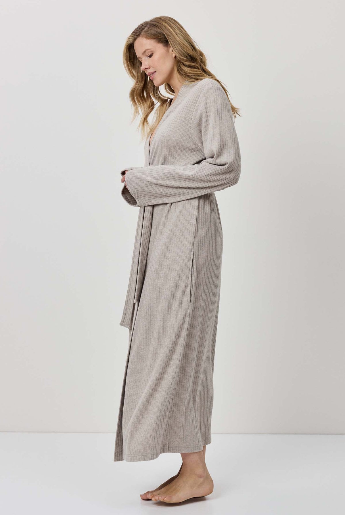 Woman wearing a long beige robe against a white background