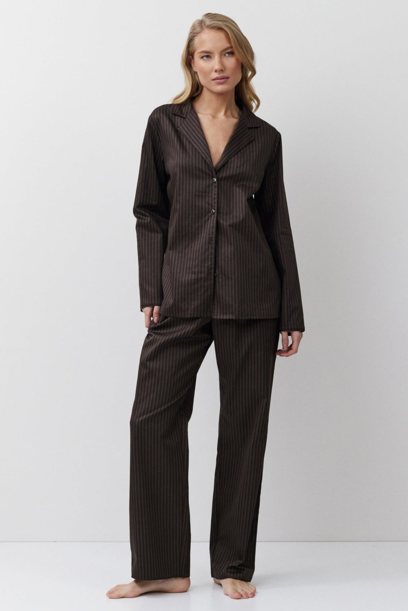 Woman wearing a black pinstripe pajama set on a white background