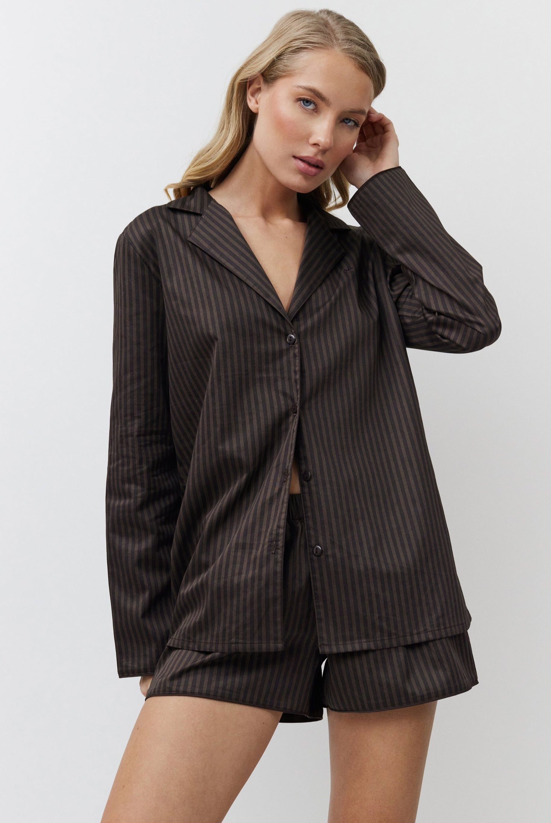 Woman wearing a brown pajama set against a white background